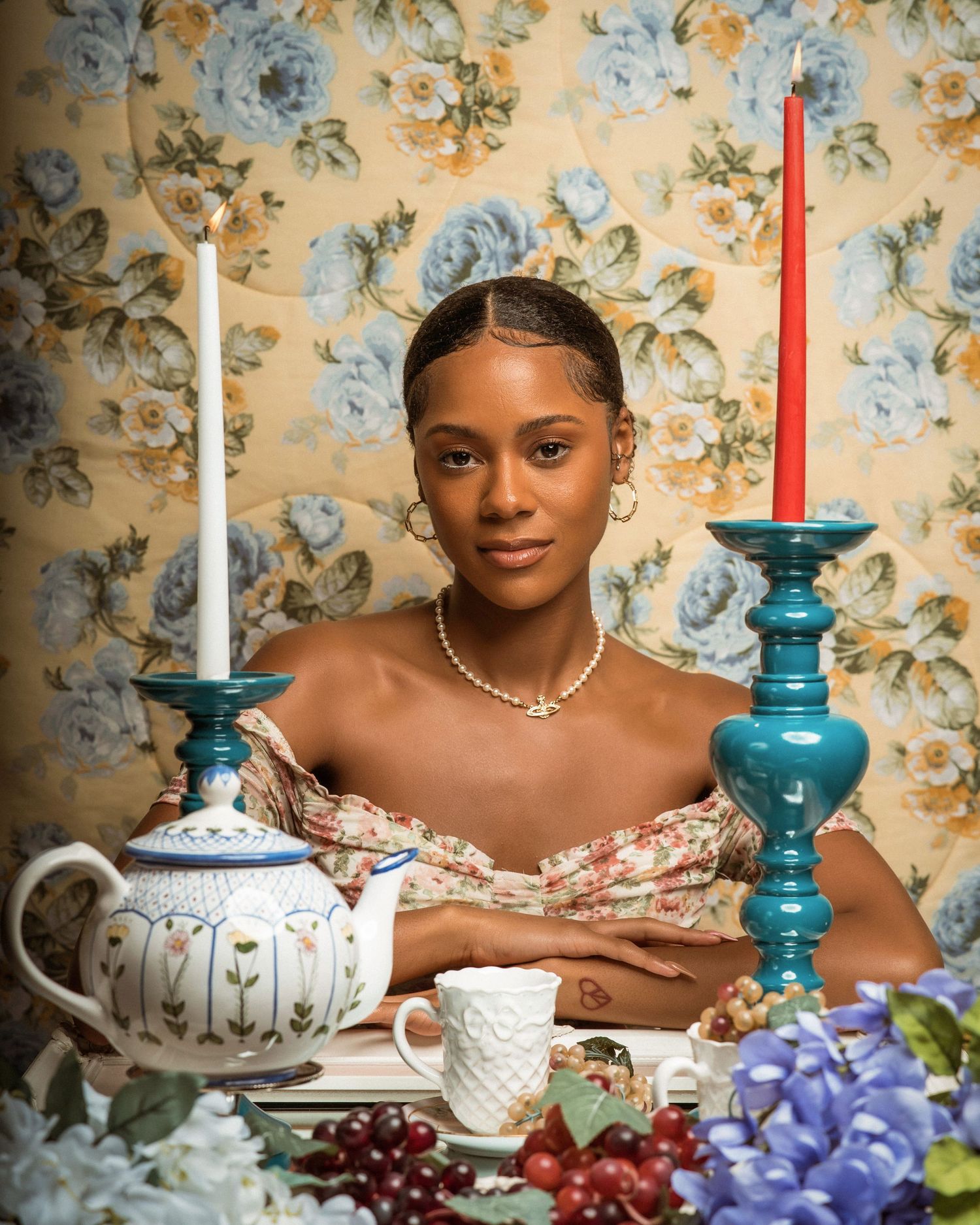 Tea party scene with white teapot, turquoise candleholders, and fresh flowers on display.