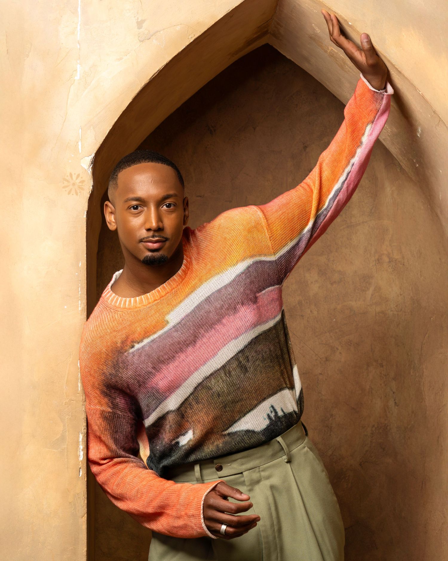 Fashion portraits featuring coral-colored sweater and olive pants in architectural setting.