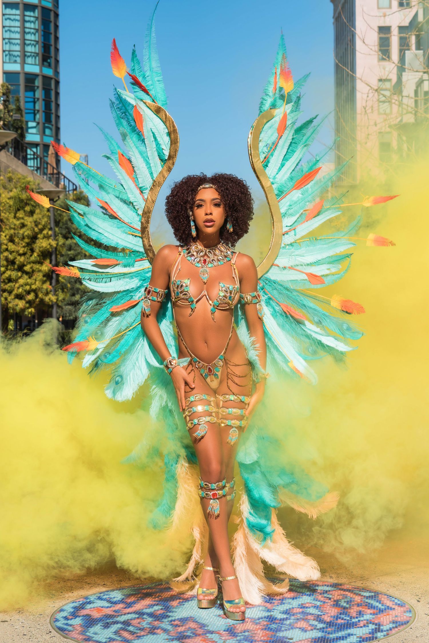 Carnival performance with yellow smoke effects and dramatic turquoise feathered wings.