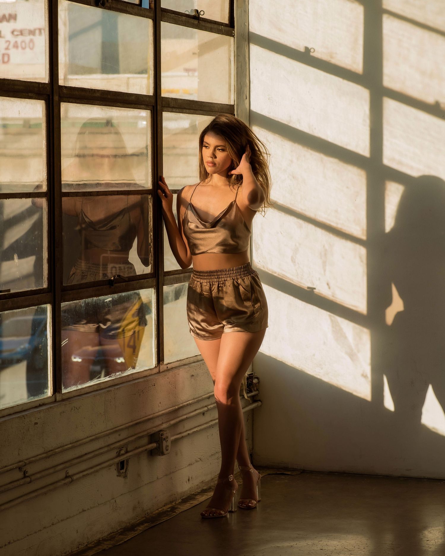Fashion photography session in industrial space with dramatic window lighting.