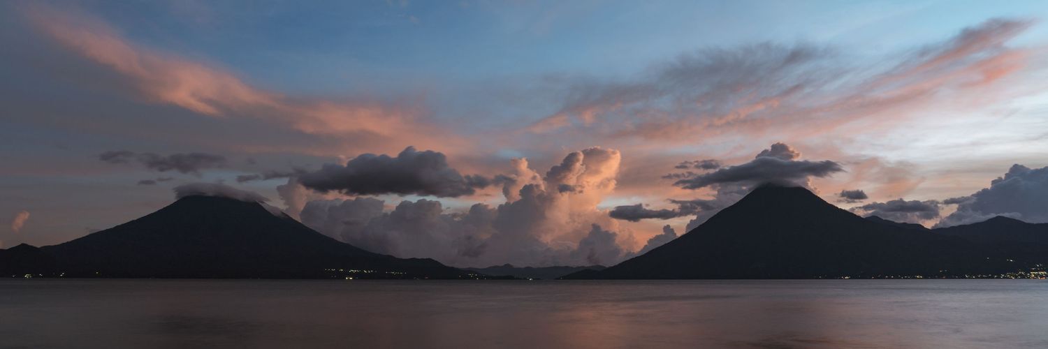 Dramatic sunset silhouettes mountains over Lake Atitlan in Guatemala.