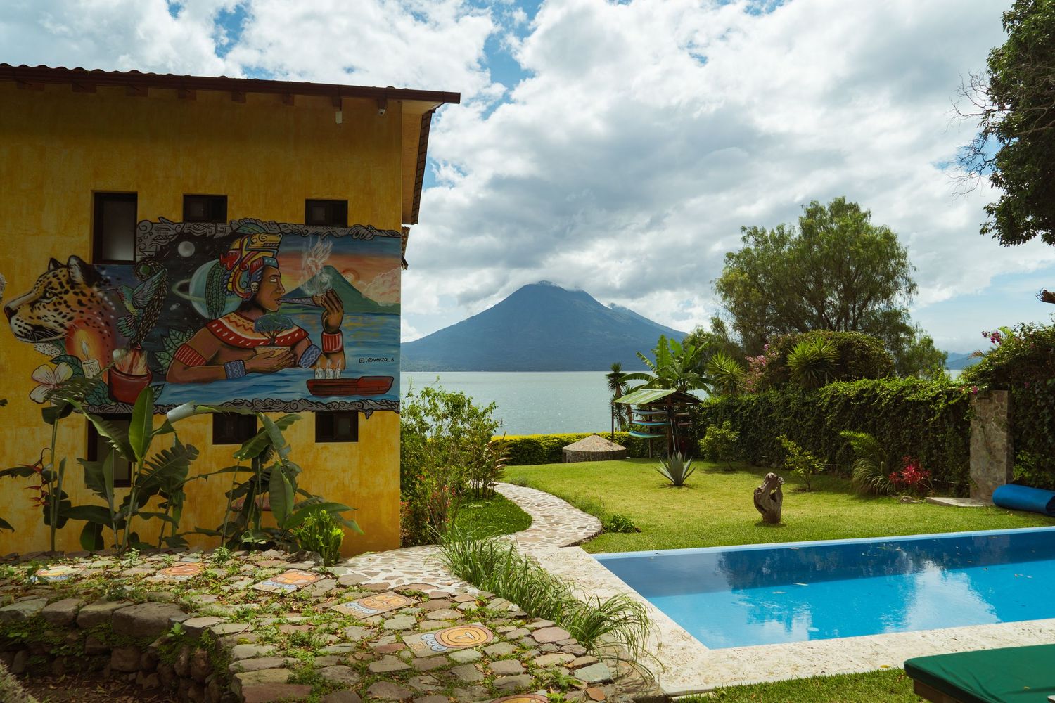 Scenic infinity pool overlooking Lake Atitlan with a majestic volcano in the background under blue skies.