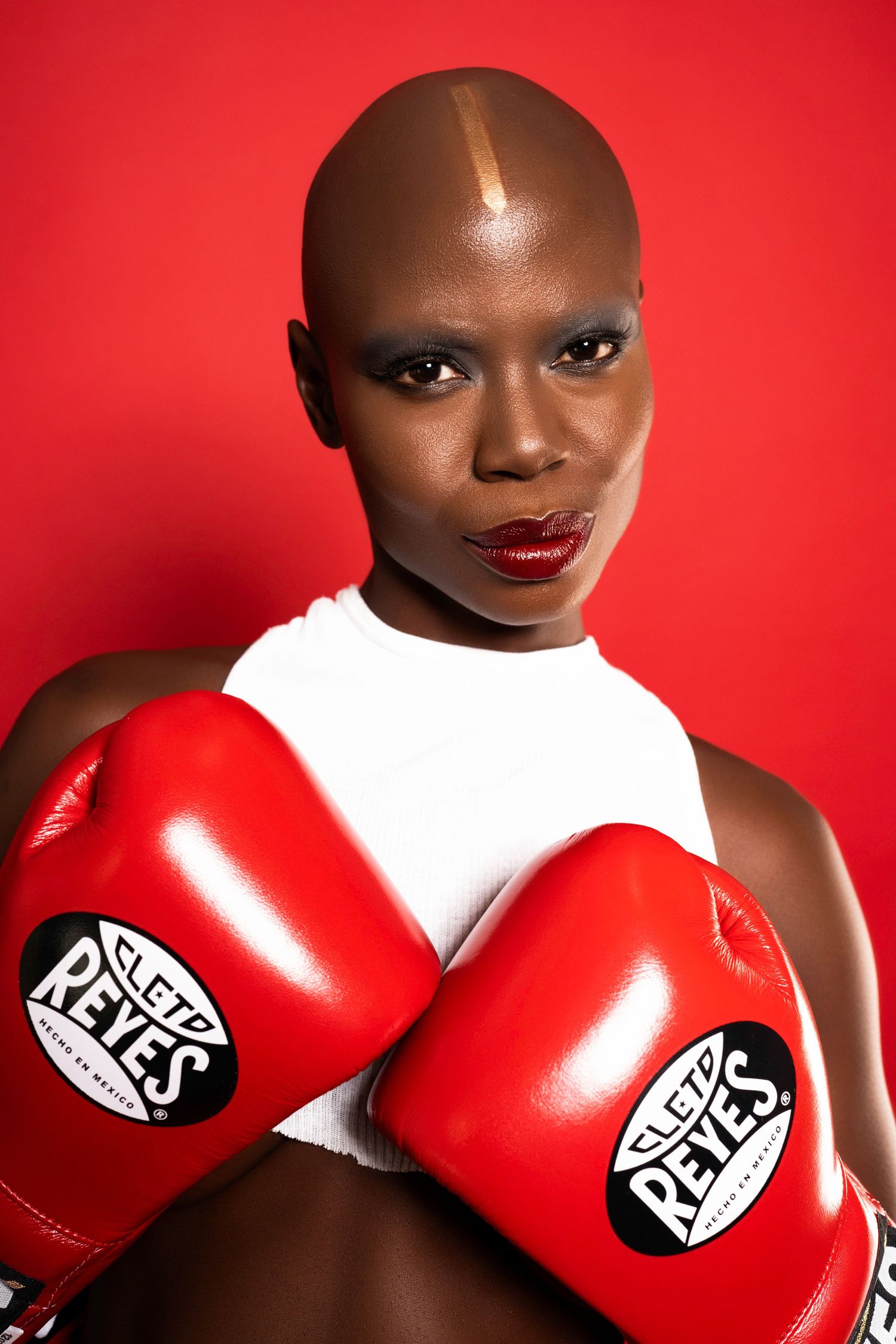 Close-up fashion portrait with red boxing gloves against bold red background.