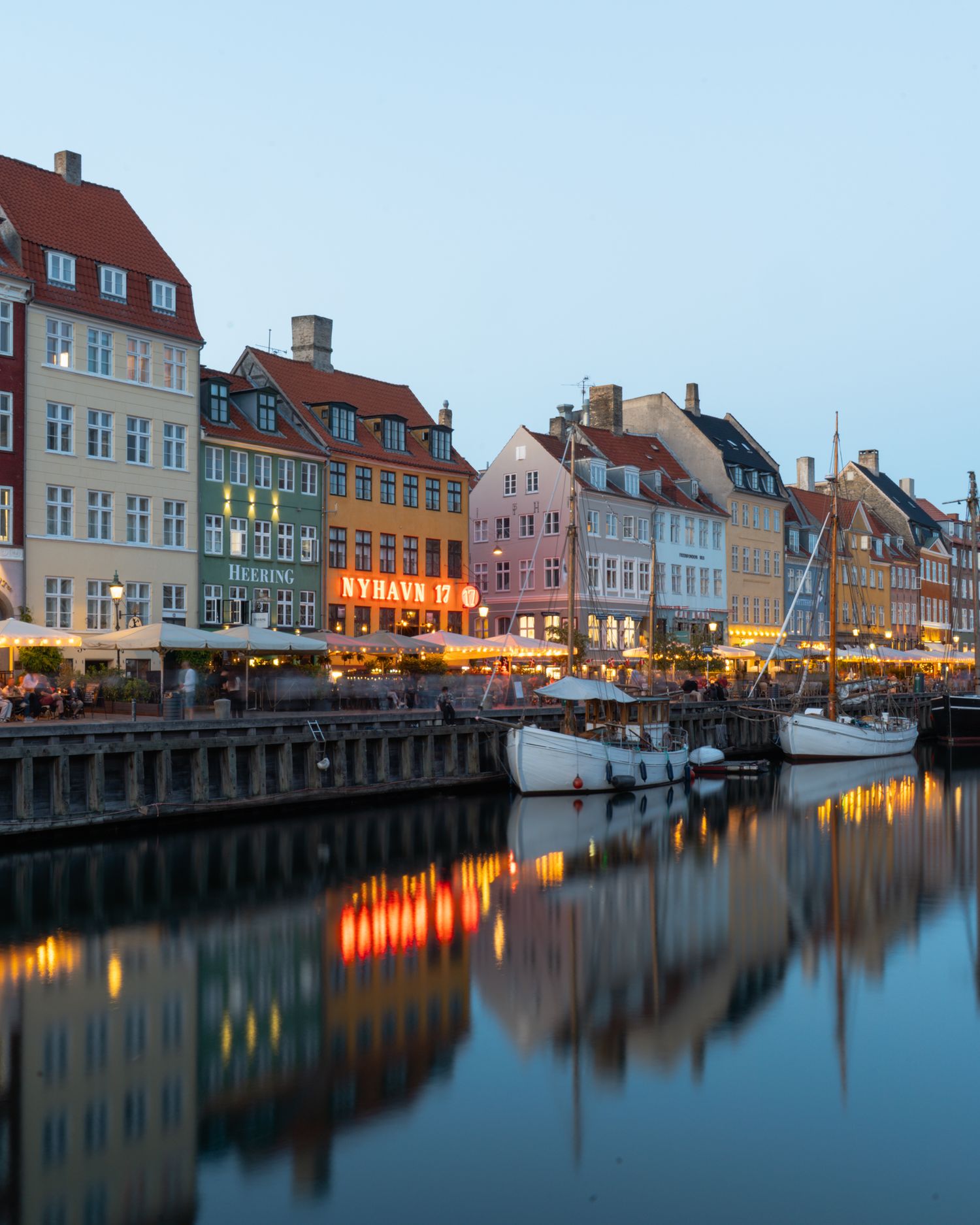 Historic colorful buildings along Nyhavn canal in Copenhagen during evening hours.