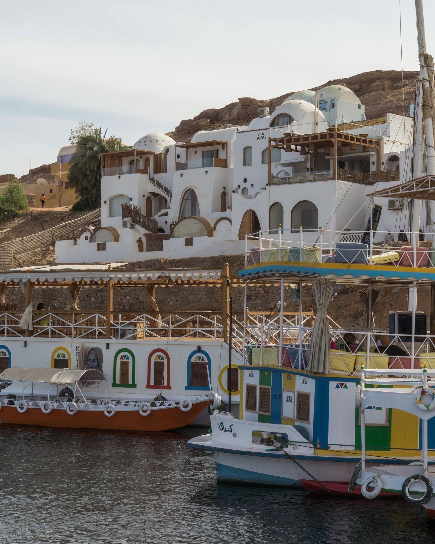 Colorful traditional boat houses with white domed architecture along Mediterranean waterfront.