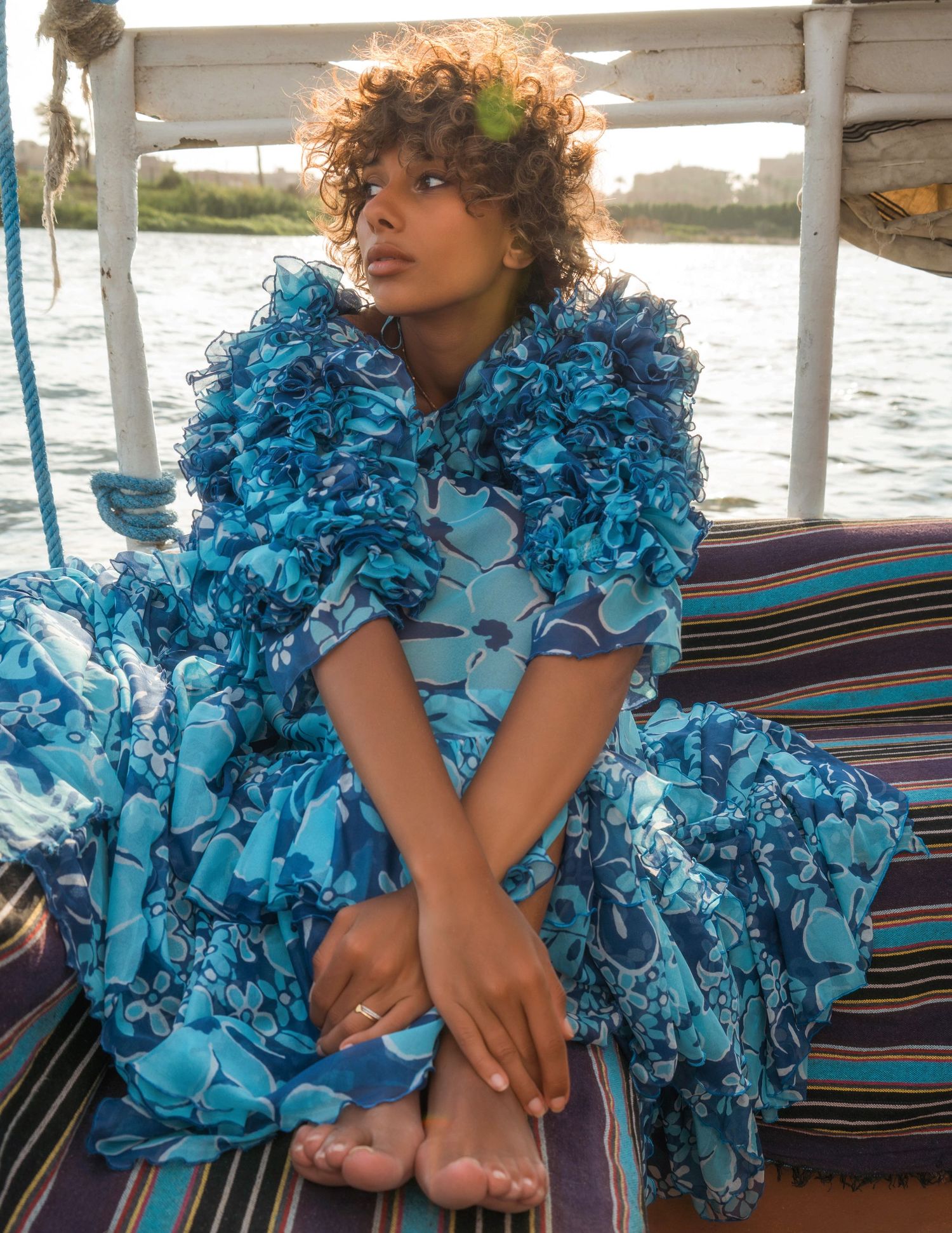 Fashion shoot featuring turquoise ruffled dress on boat deck with water views.