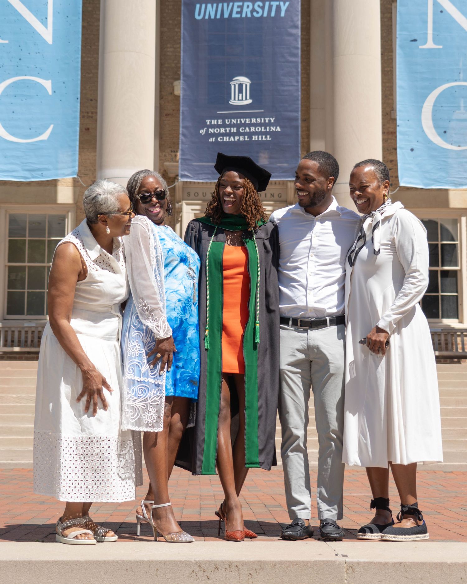 UNC Chapel Hill graduation photo with five family members posing together in front of university building.