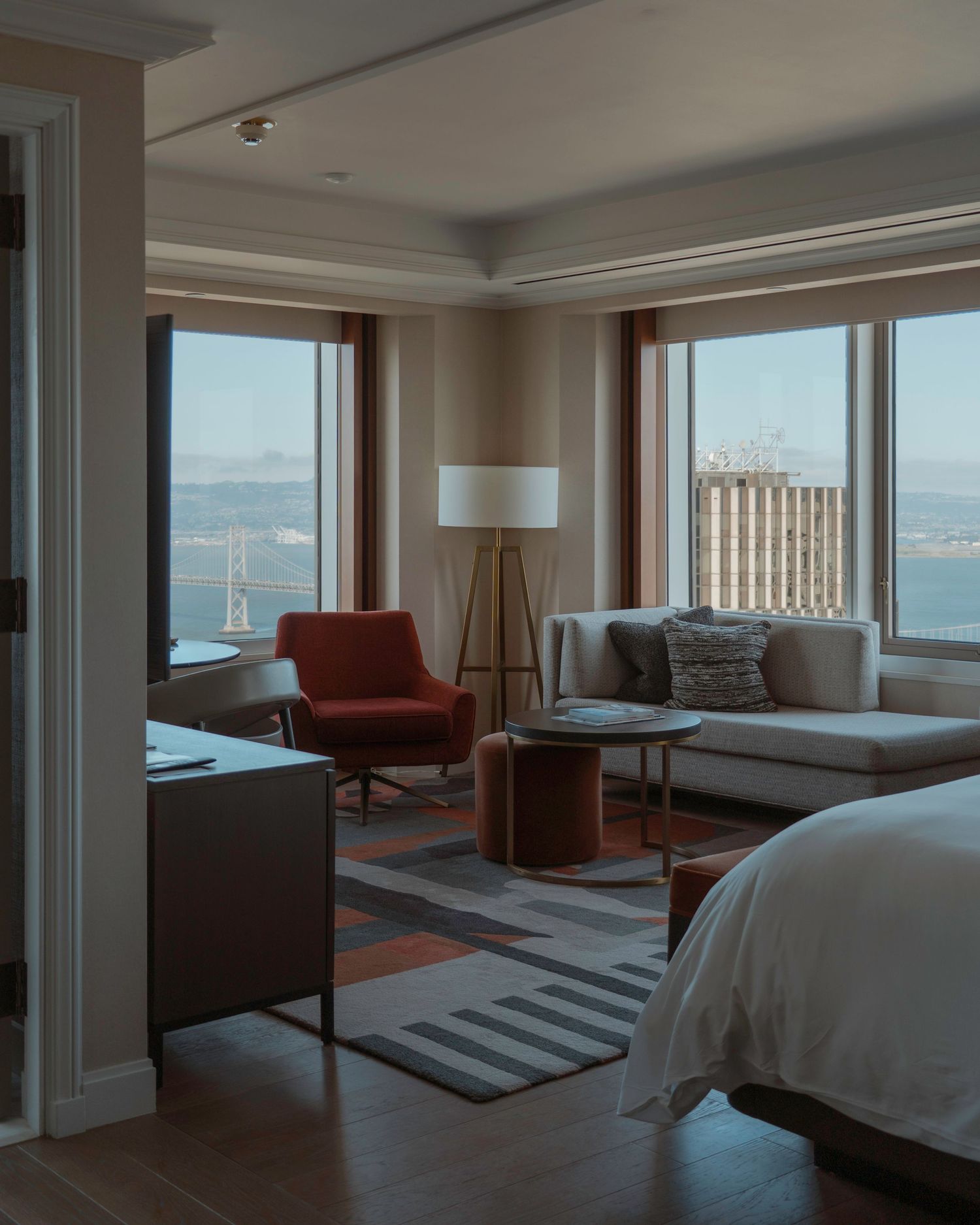 Luxurious hotel suite interior with modern furnishings and large windows overlooking the bay.