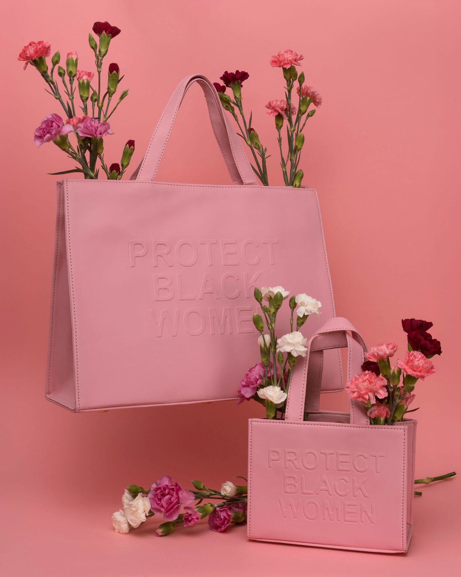Pink embossed tote bags displayed with pink and red carnation flowers against pink background.