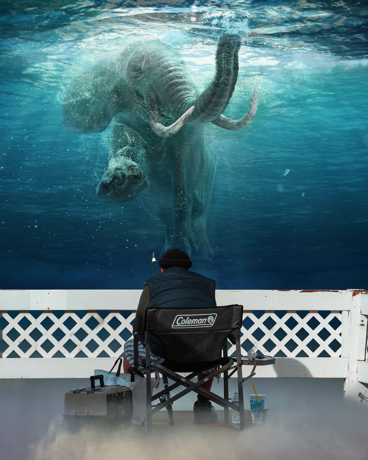 Surreal underwater view of elephant swimming above person sitting in camping chair.