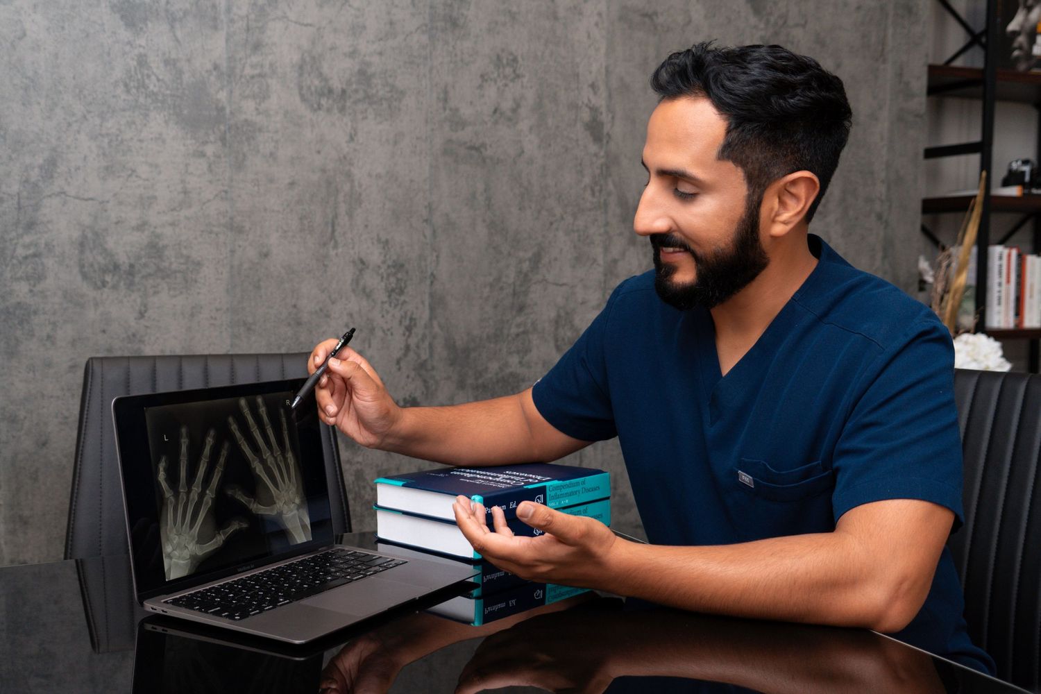 Medical professional in scrubs reviews information on a mobile device while sitting at a desk.