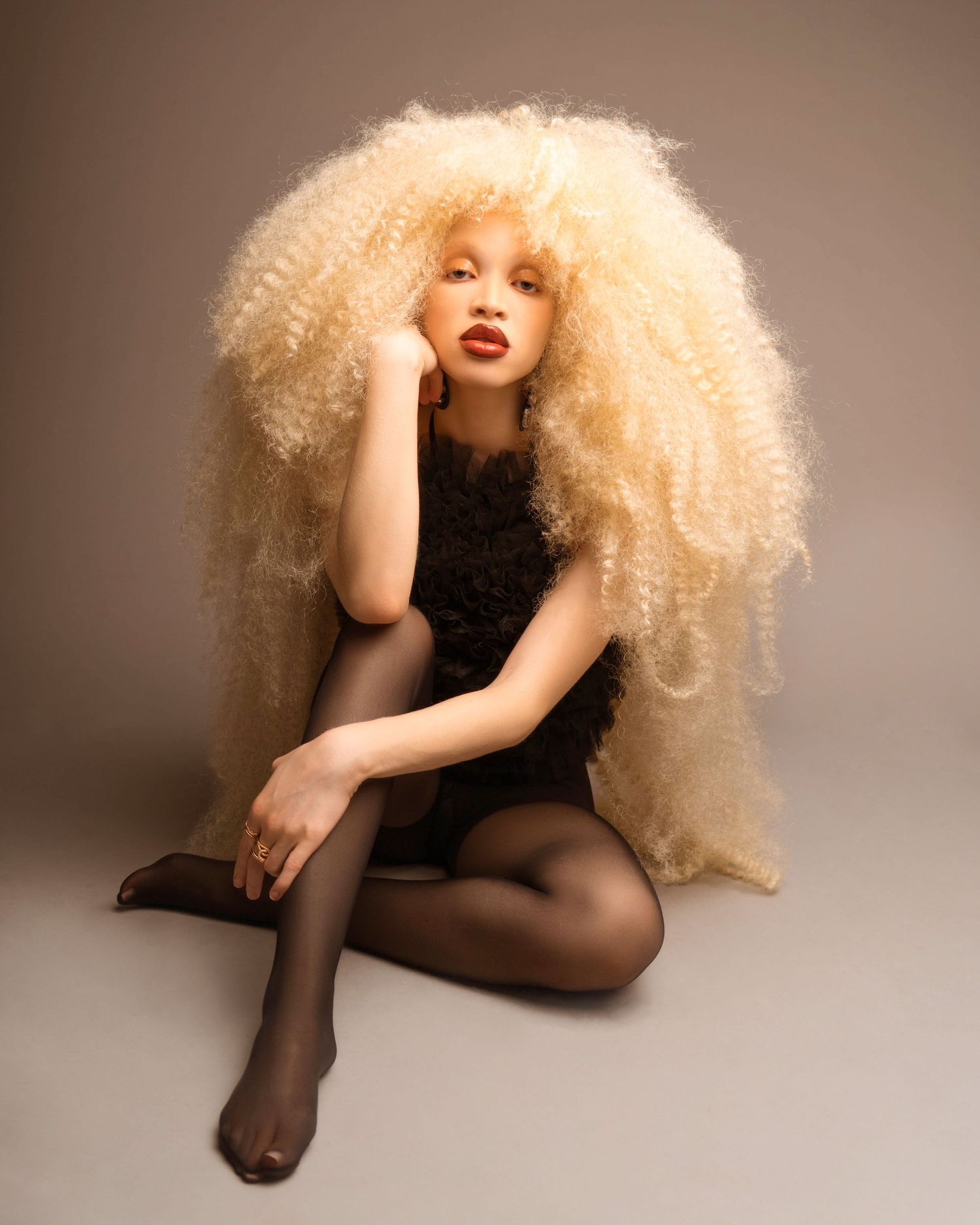 Fashion portrait series with voluminous blonde curly hair and black clothing.