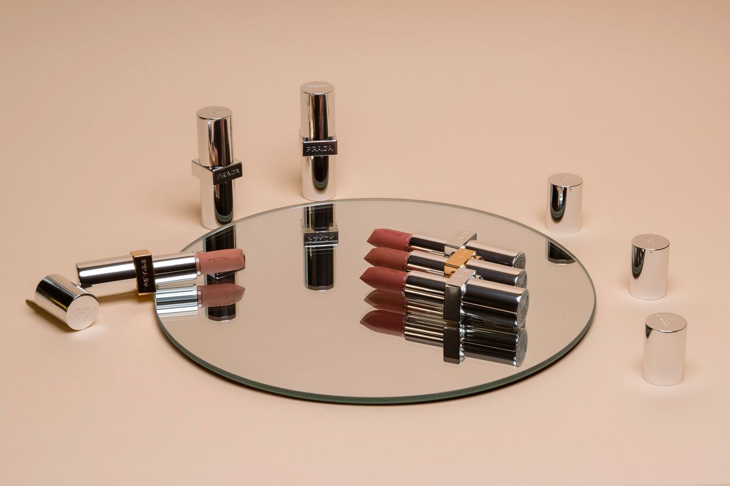Collection of luxury lipsticks and makeup products arranged on a round mirror.