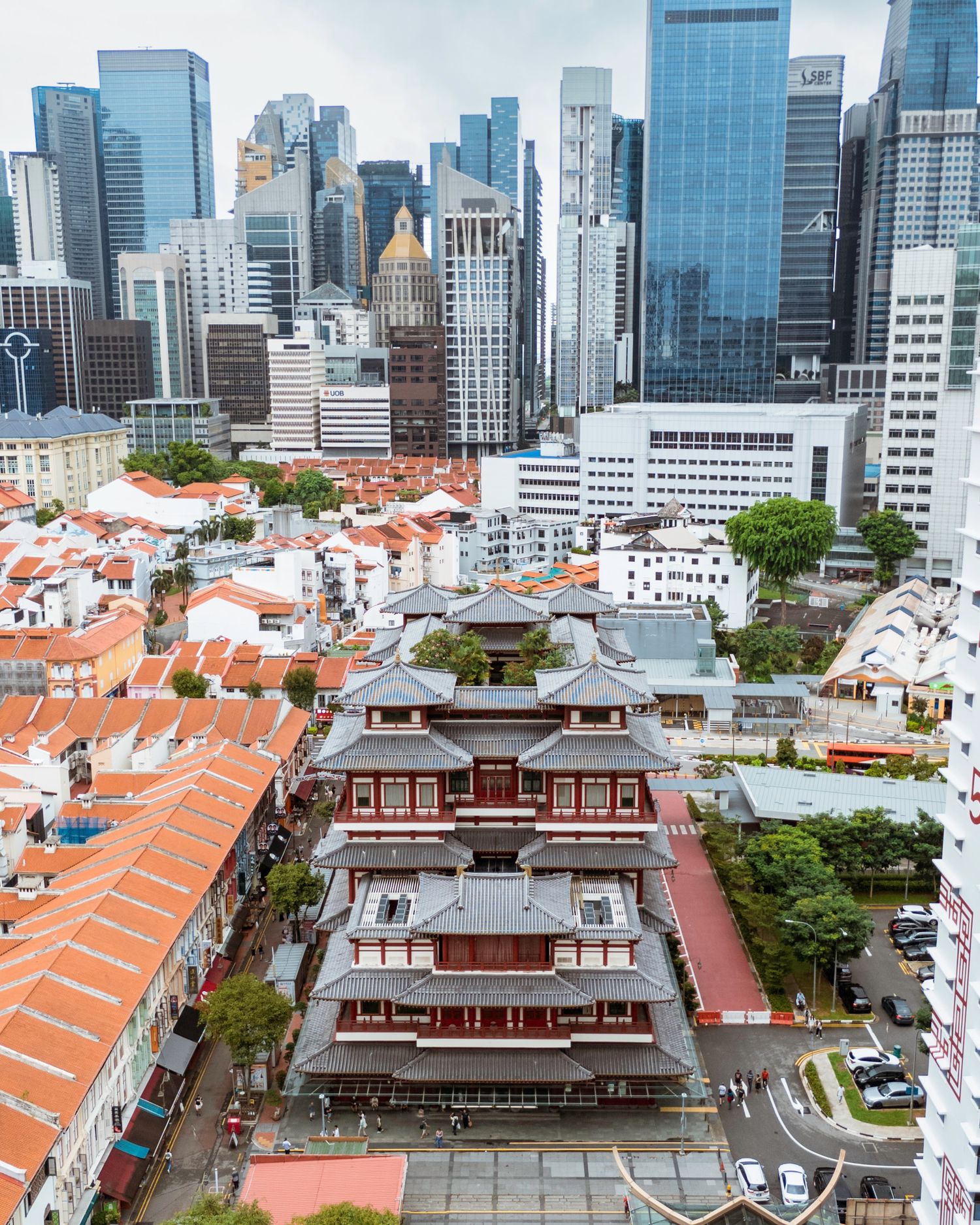 Historic shophouses with terracotta roofs contrasting against modern skyscrapers in Singapore's downtown.