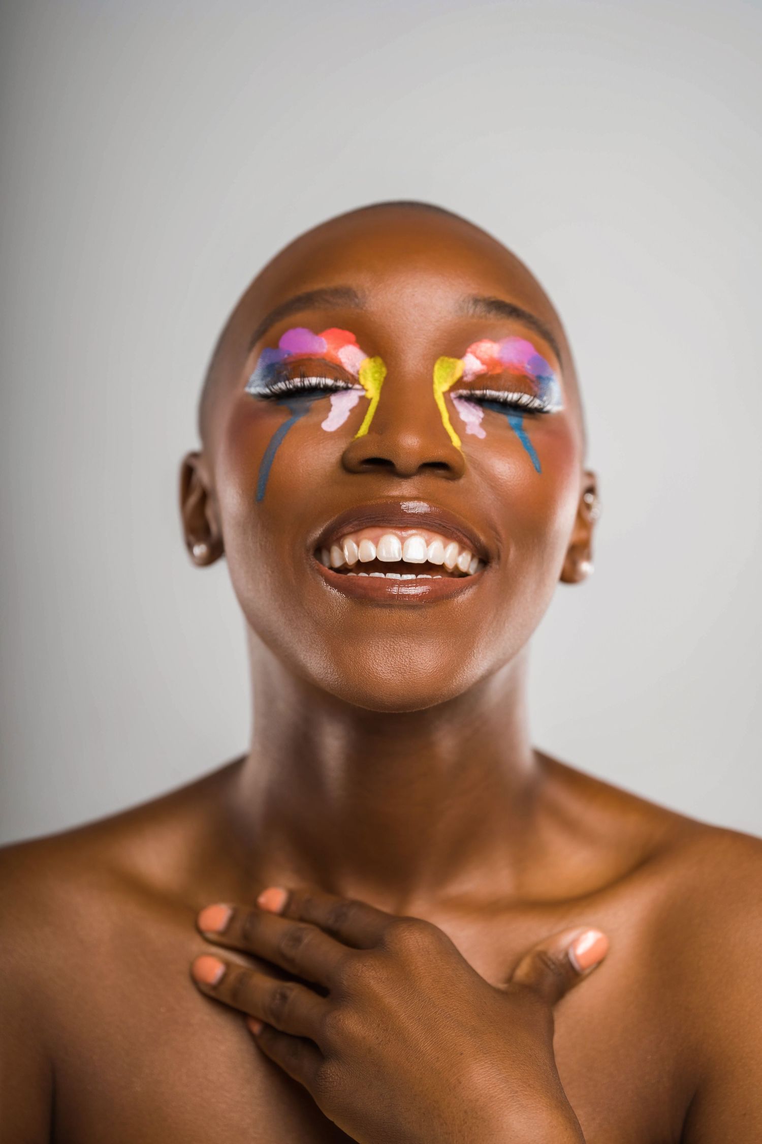 Close-up beauty shots showing vibrant rainbow eye makeup with artistic teardrops on dark skin.