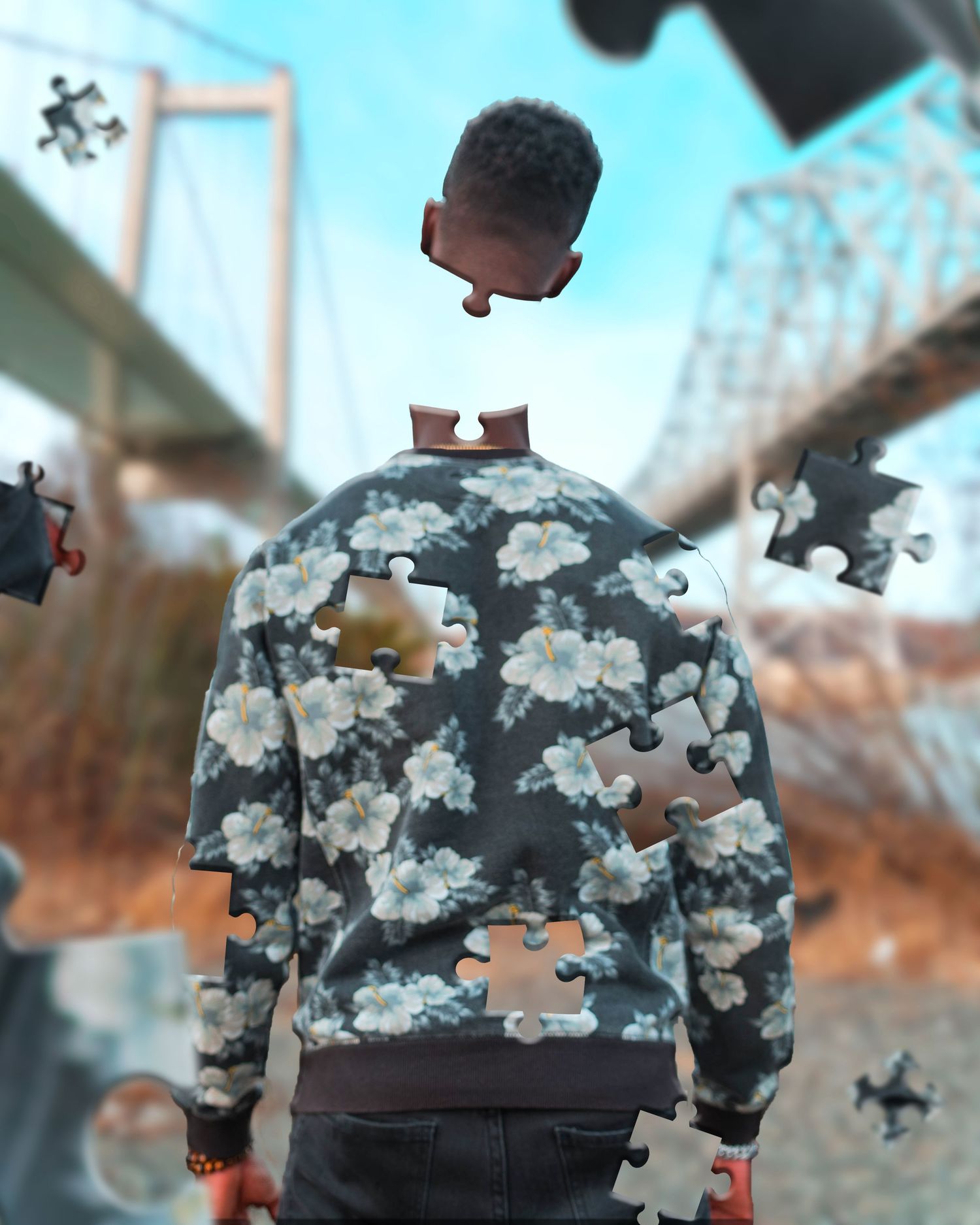 Surreal photo of a person wearing camo jacket dissolving into puzzle pieces near a bridge.