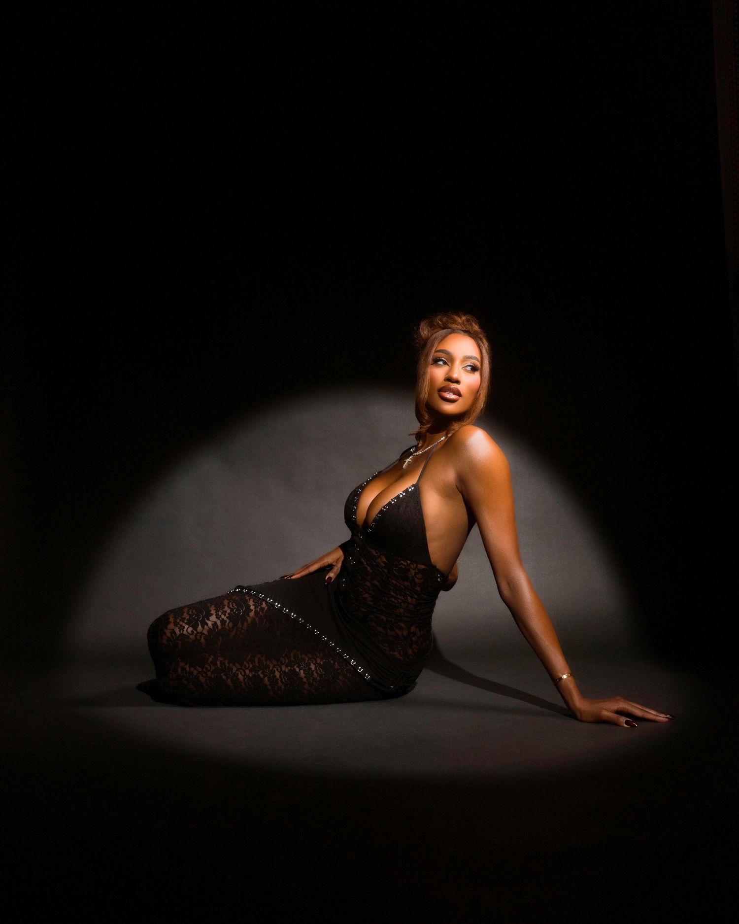 Low-key dramatic portrait series with spotlight effect on model in black dress.