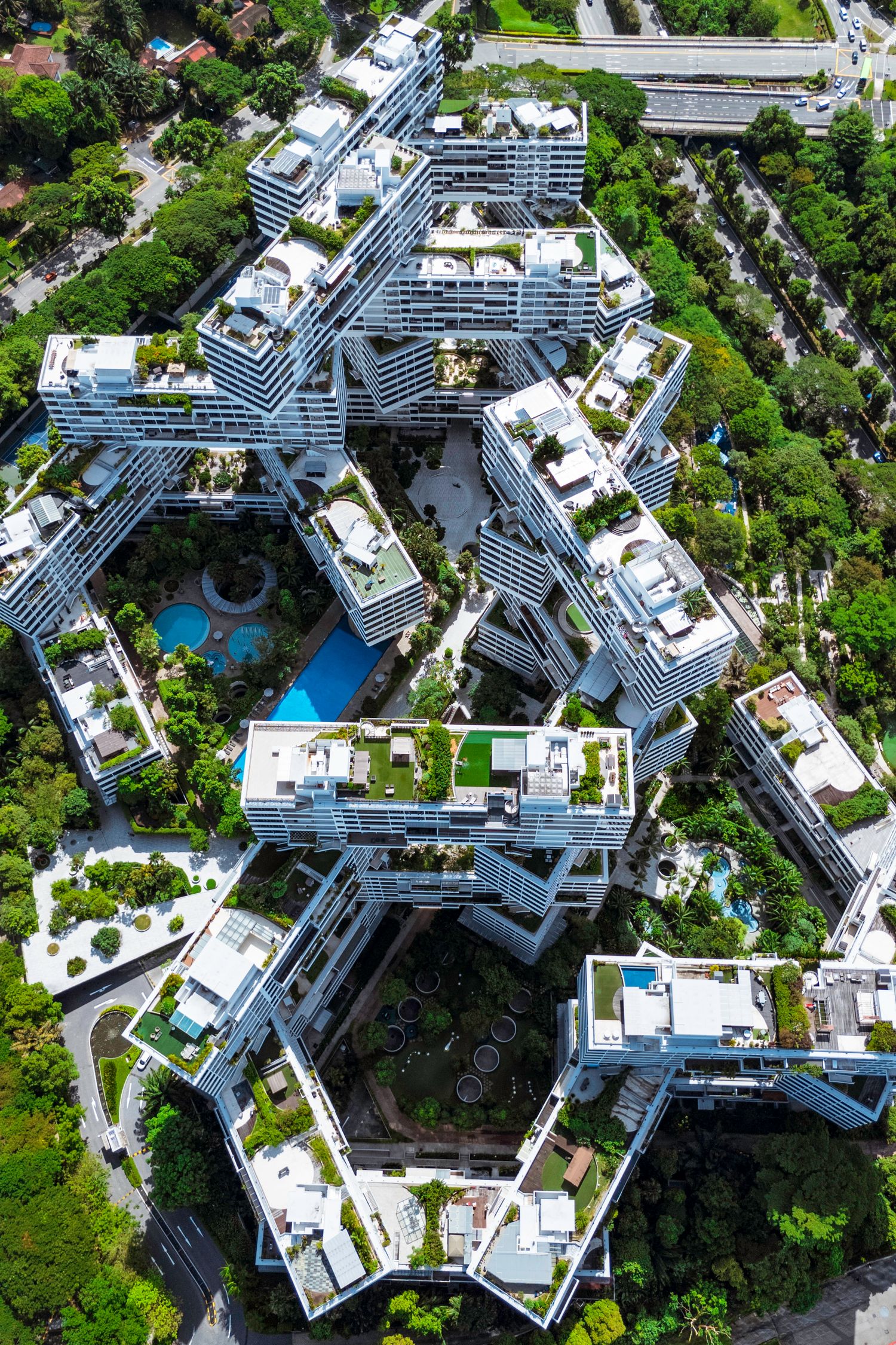 Modern luxury condominium complex with swimming pools and landscaped gardens viewed from above.