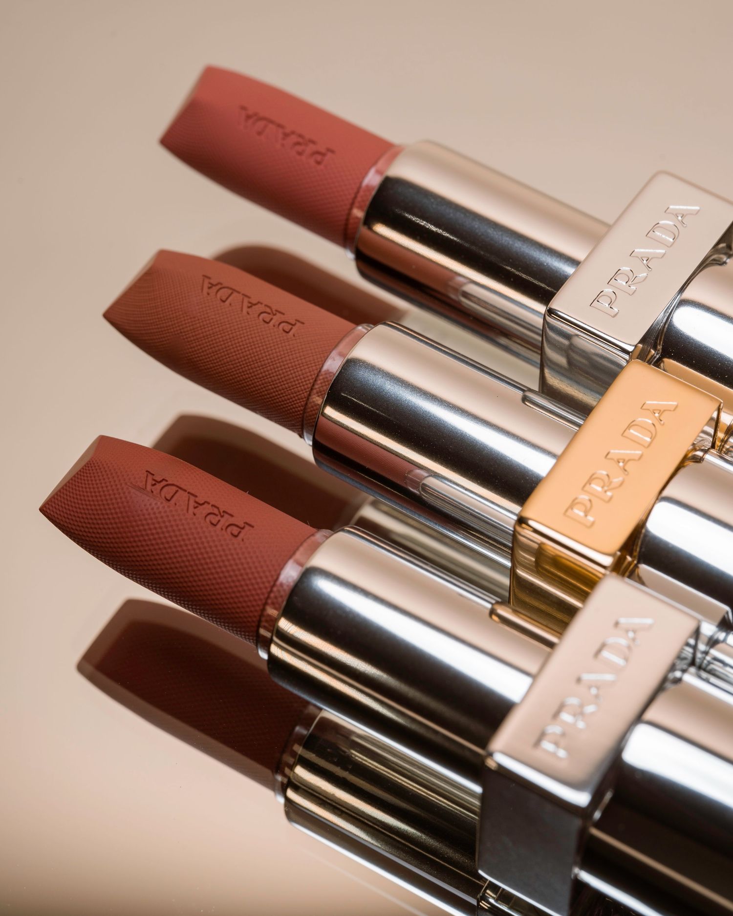 Collection of nude-toned lipsticks lined up against beige background.