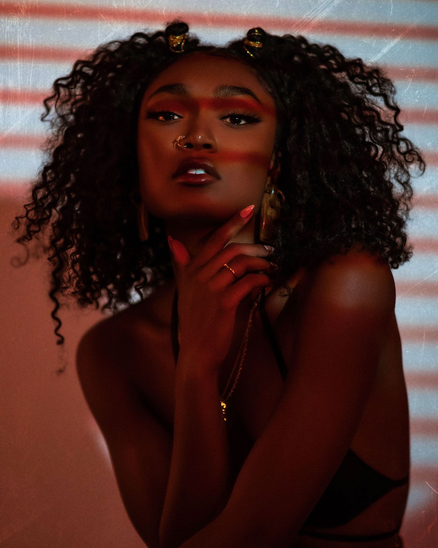 Artistic beauty portrait with dramatic lighting and curly hair against warm-toned background.