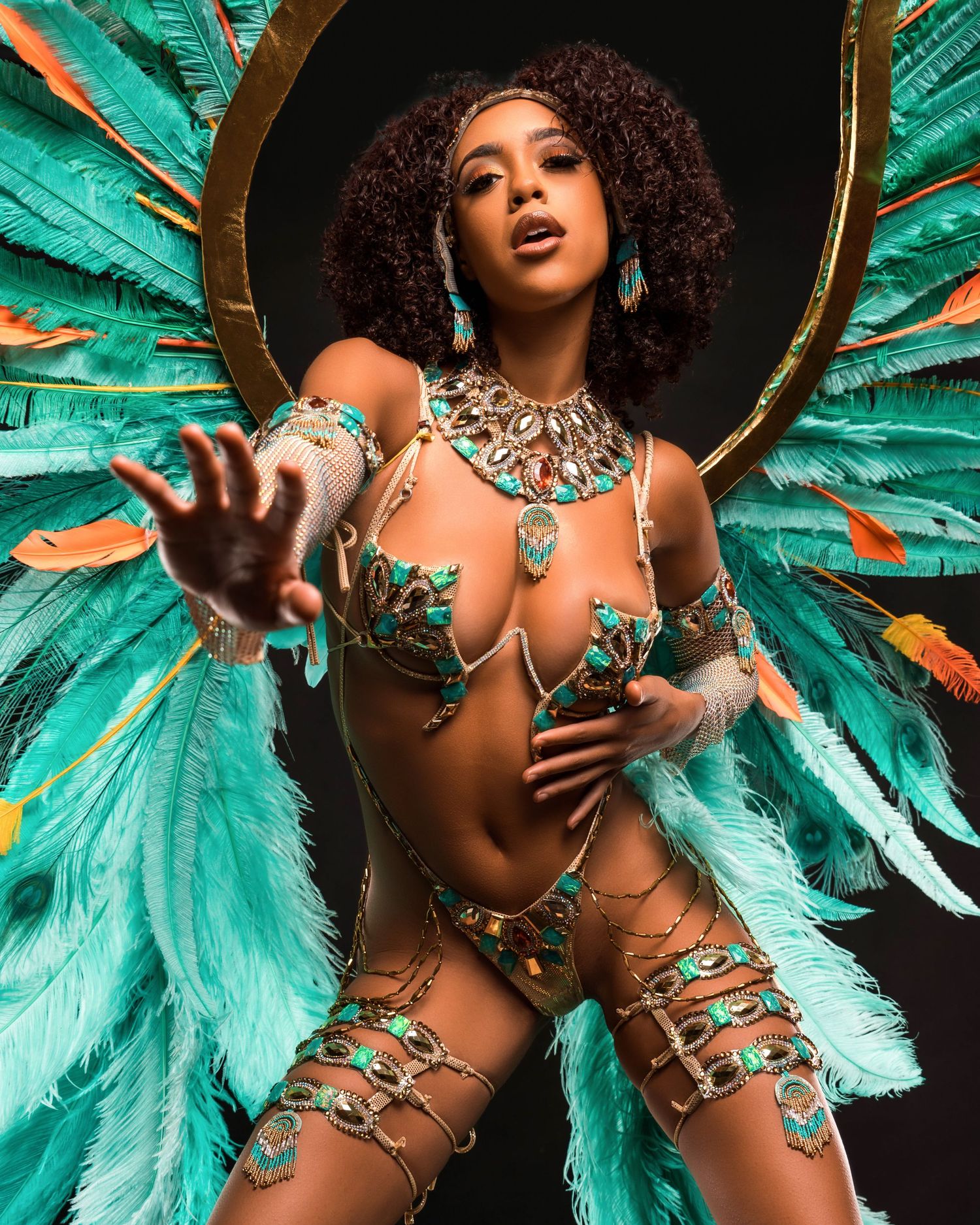 Dramatic portrait in carnival attire with turquoise feathers and gold accessories.