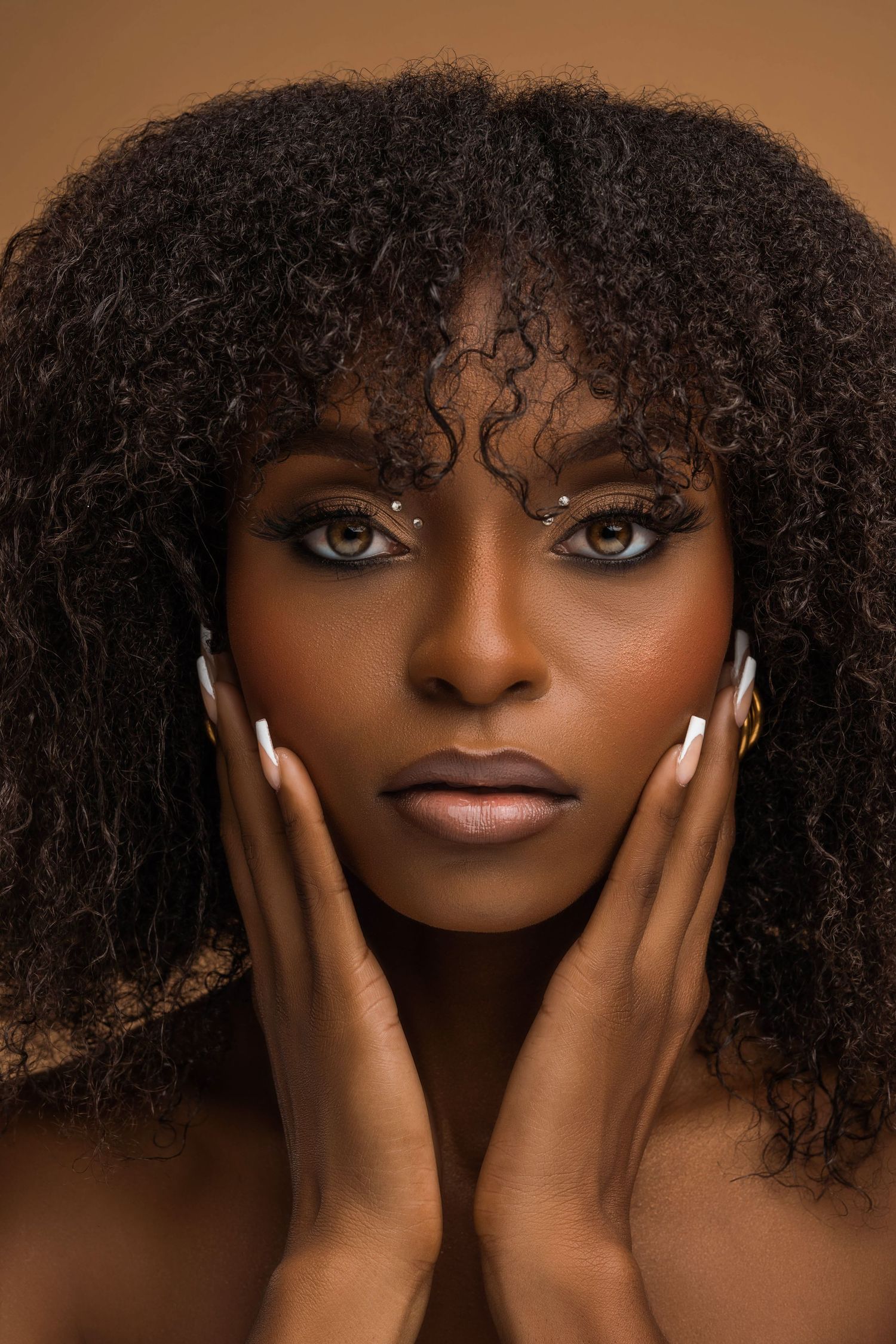 Intimate beauty close-up of a woman with curly hair and soft makeup, gazing into the camera with a cinematic lighting style.
