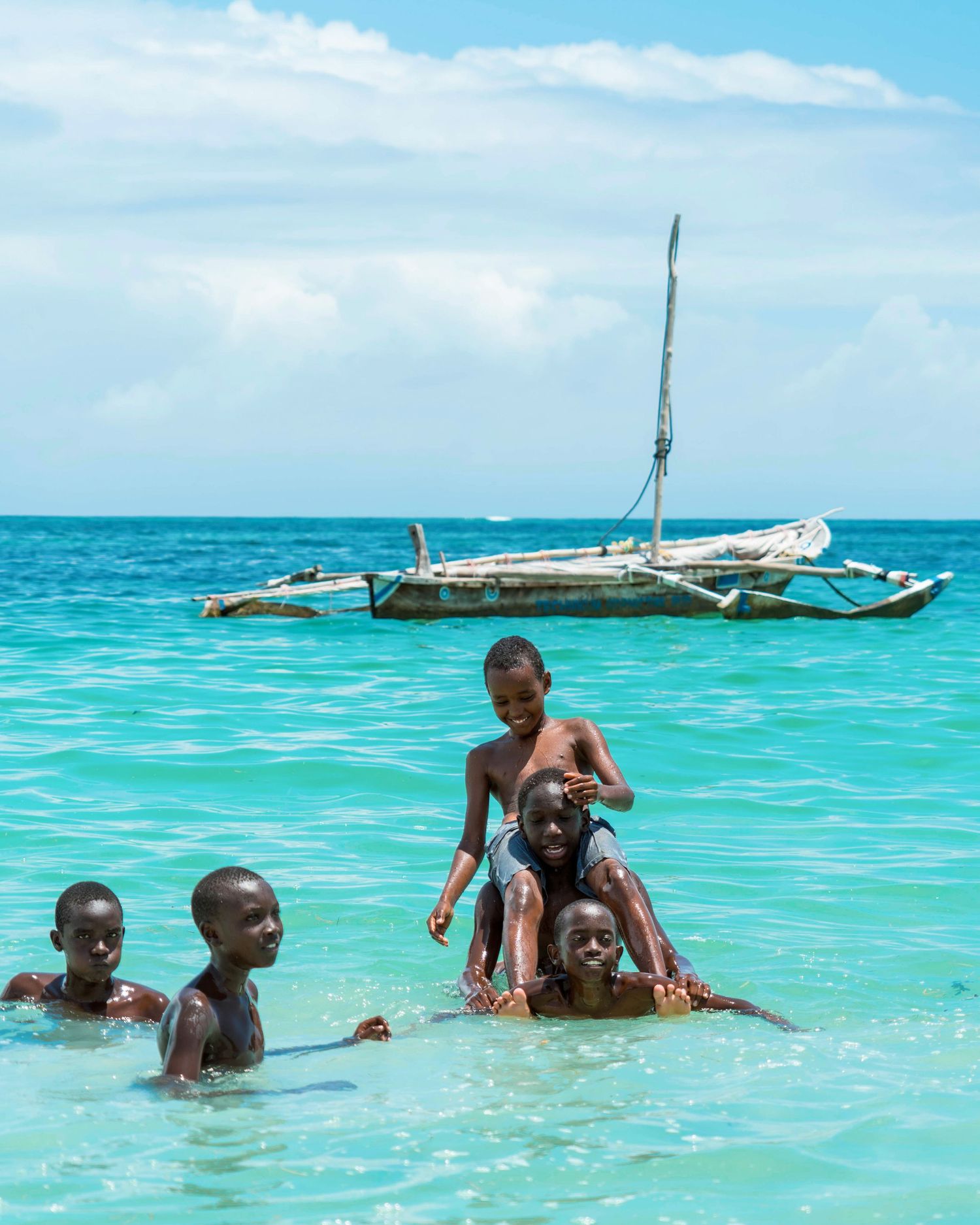 Traditional wooden sailing boat anchored in crystal clear turquoise tropical waters.