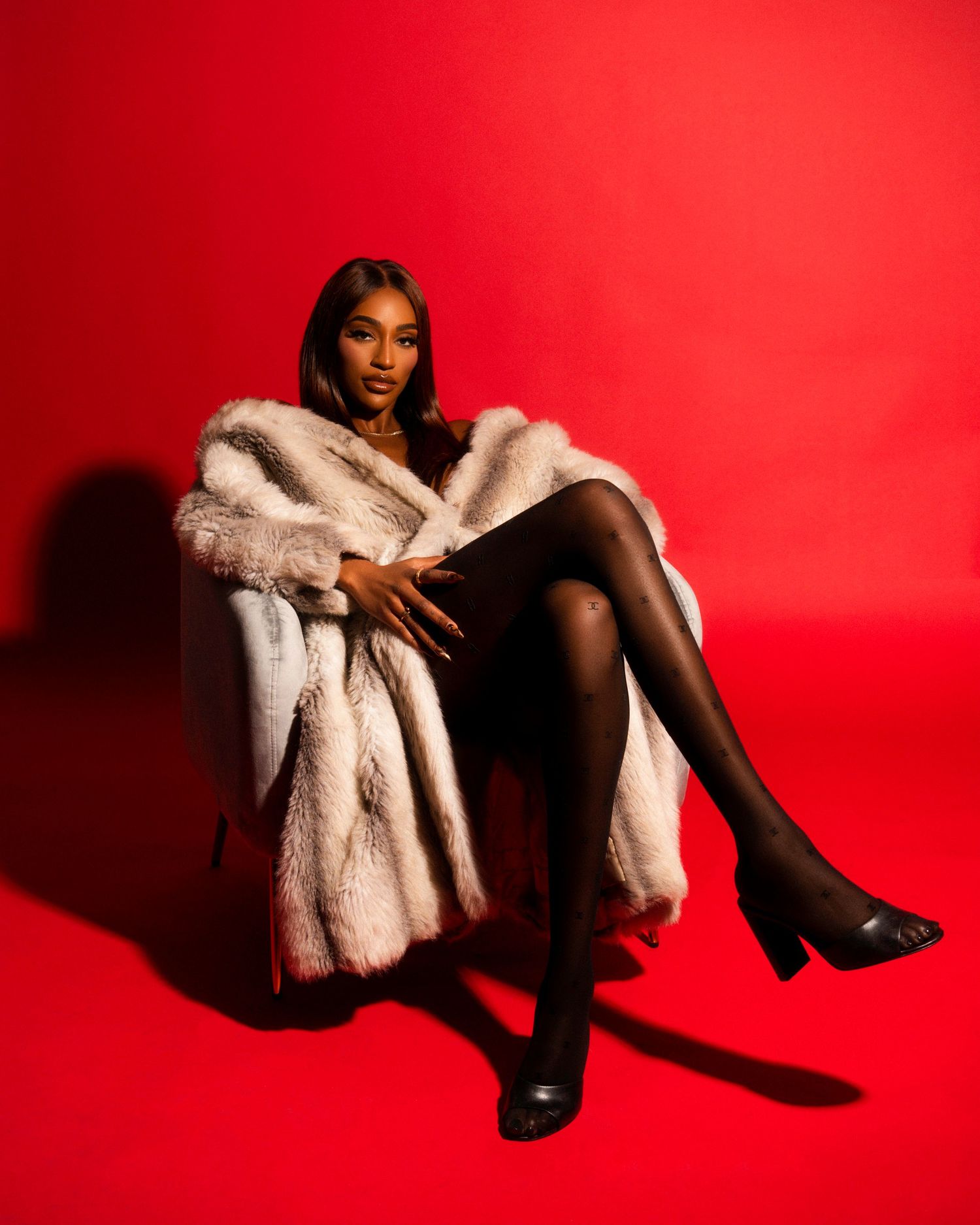 Stylish portrait series with model in fur coat against vibrant red background.
