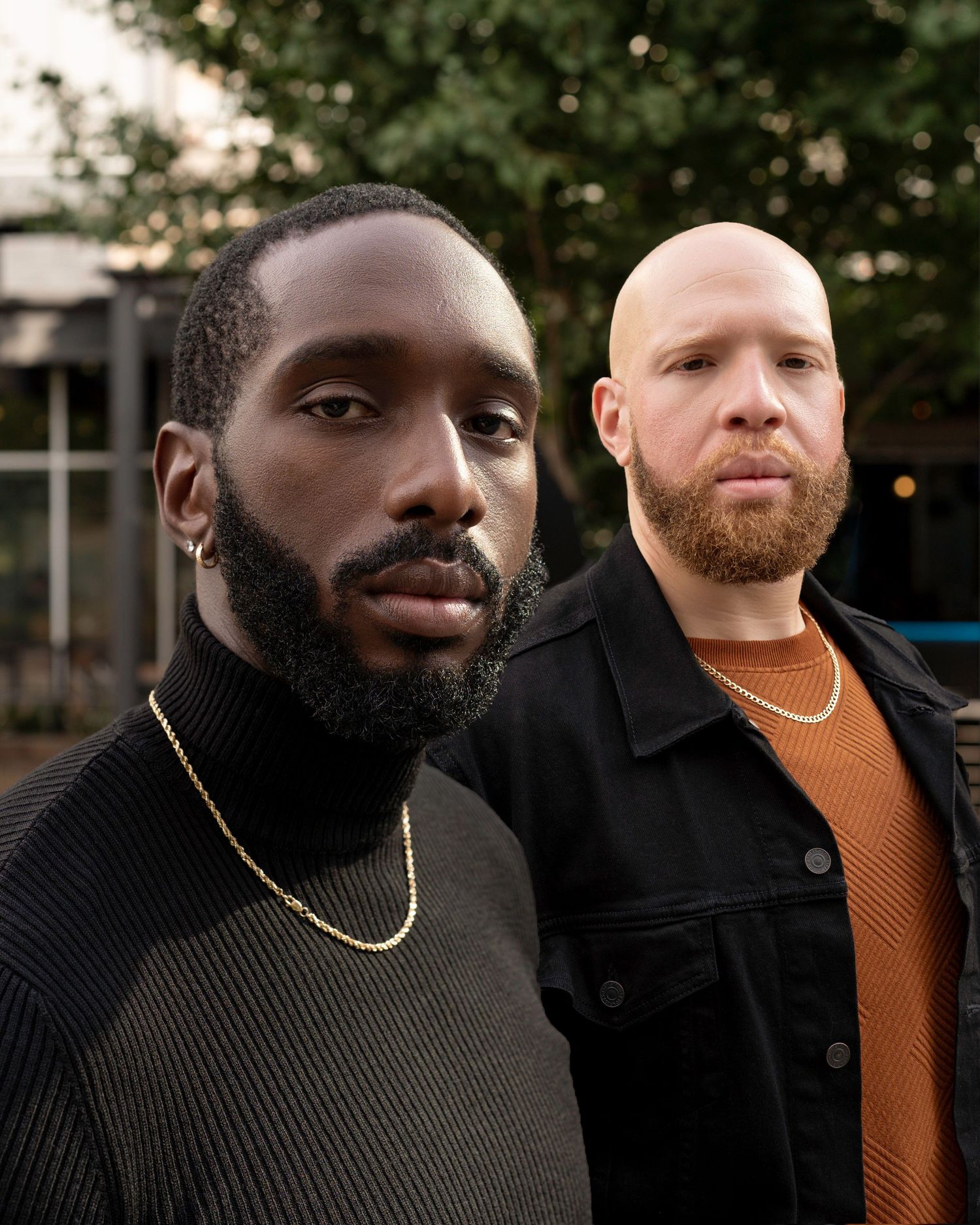 Two people wearing dark sweaters standing outdoors at dusk.