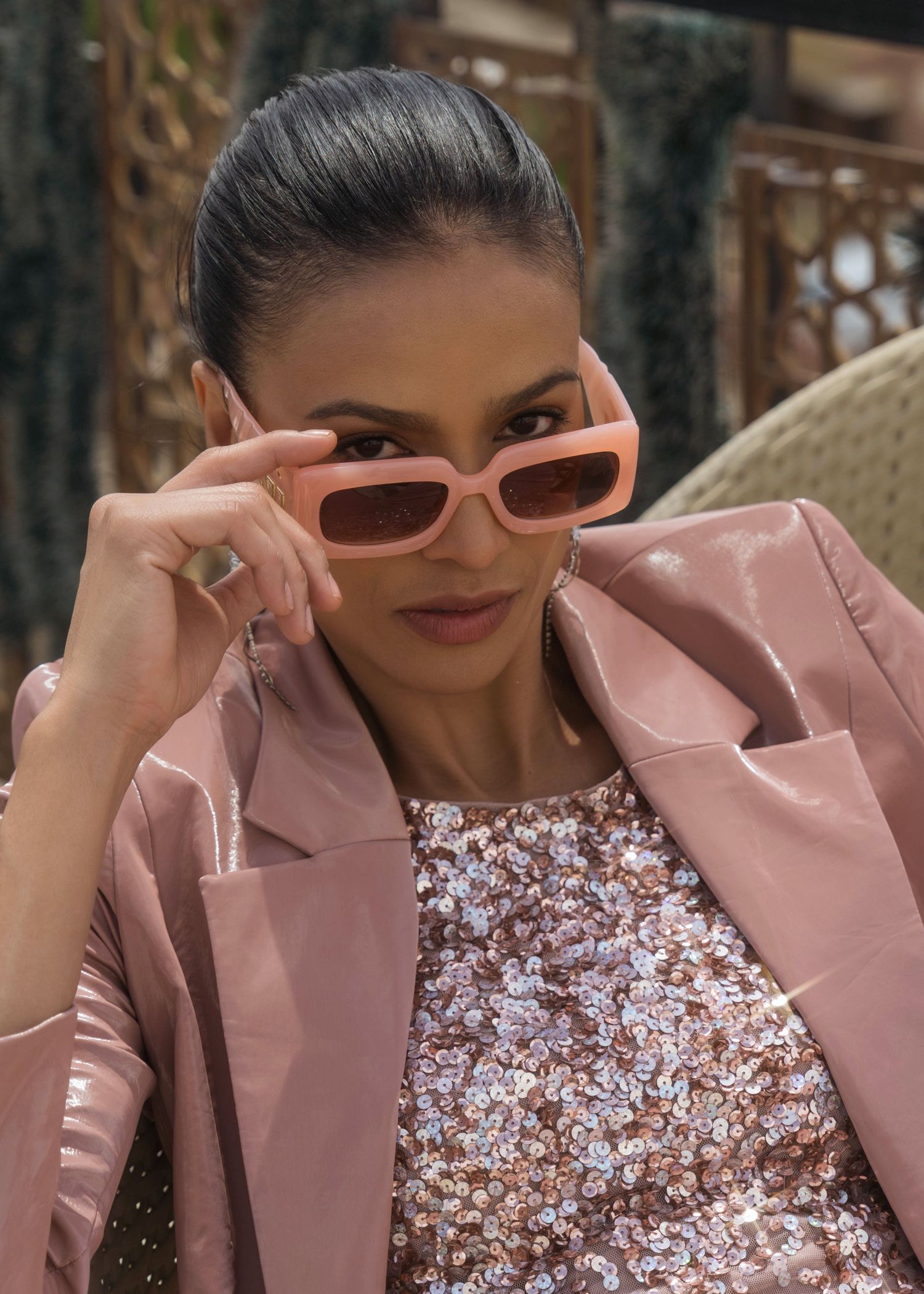 Close-up fashion shot with pink sunglasses and sequined top.