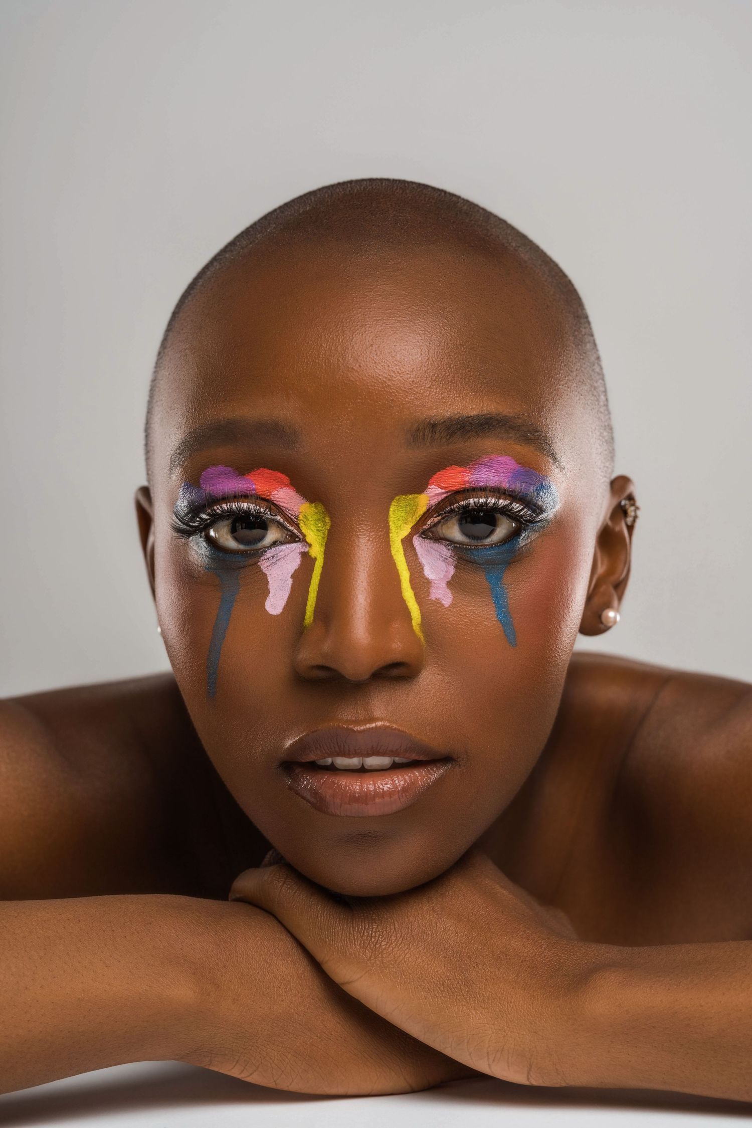 Series of creative beauty shots showing colorful dripping paint makeup design on dark skin.