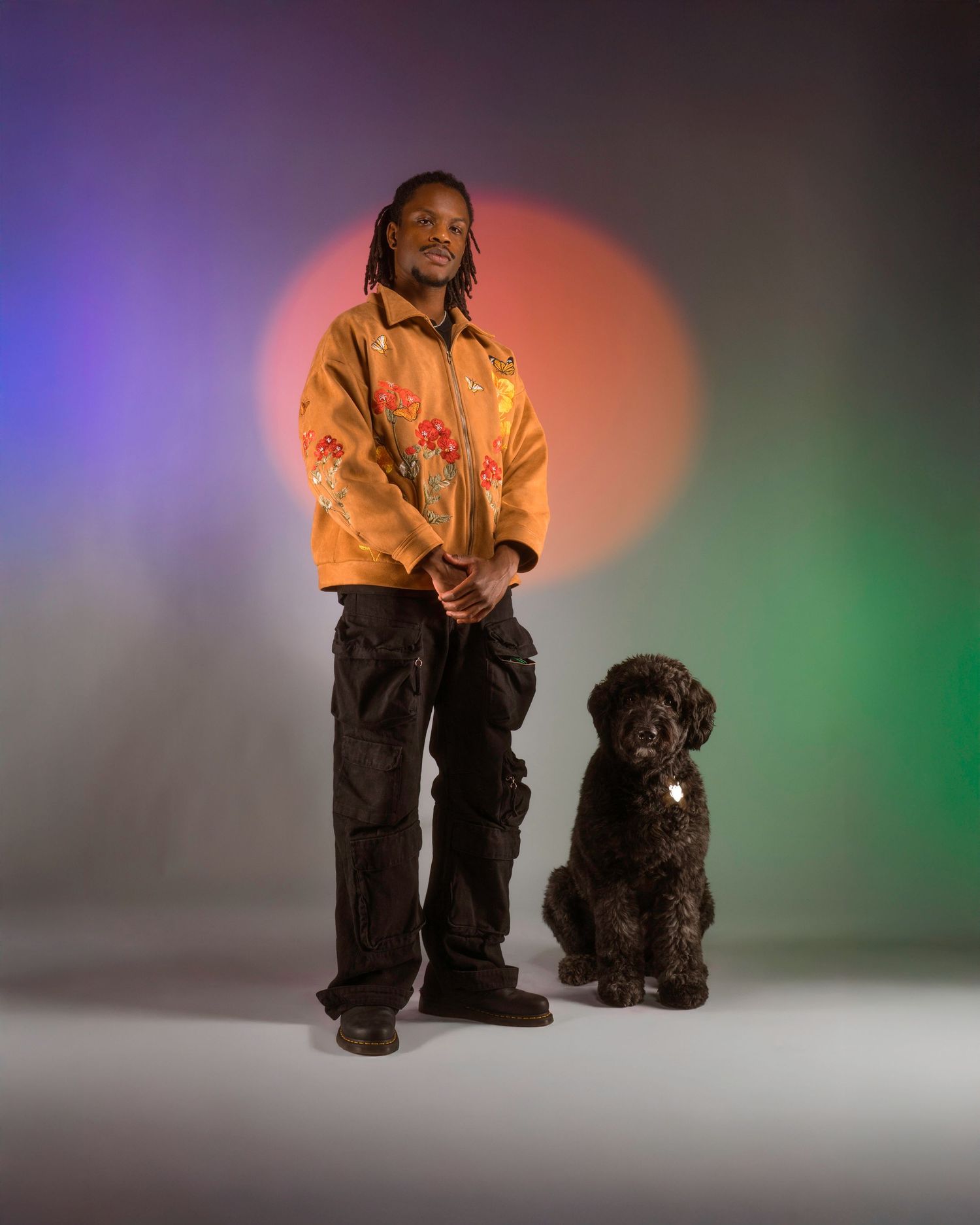 Isaiah Everett in studio lighting with his dog, blending personality, color, and creative expression.