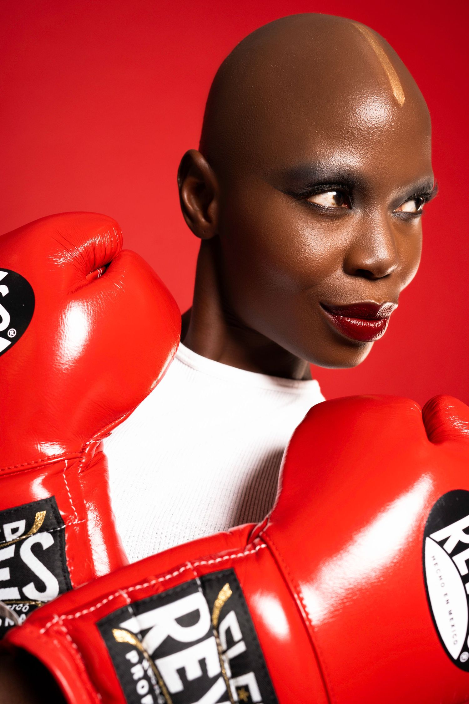 Artistic portrait against red background featuring red boxing gloves and dramatic lighting.