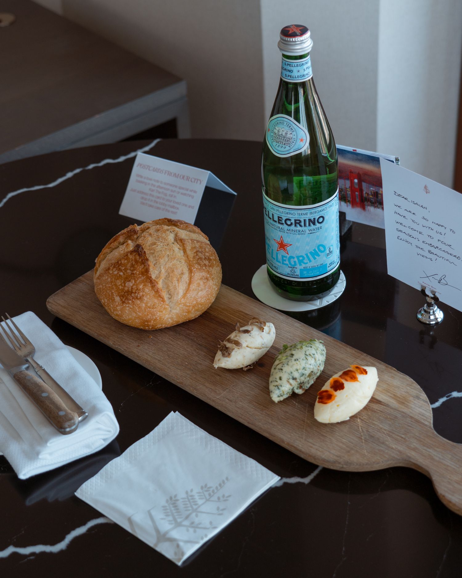 Artisanal bread and beverages arranged on a wooden cutting board with white napkins.