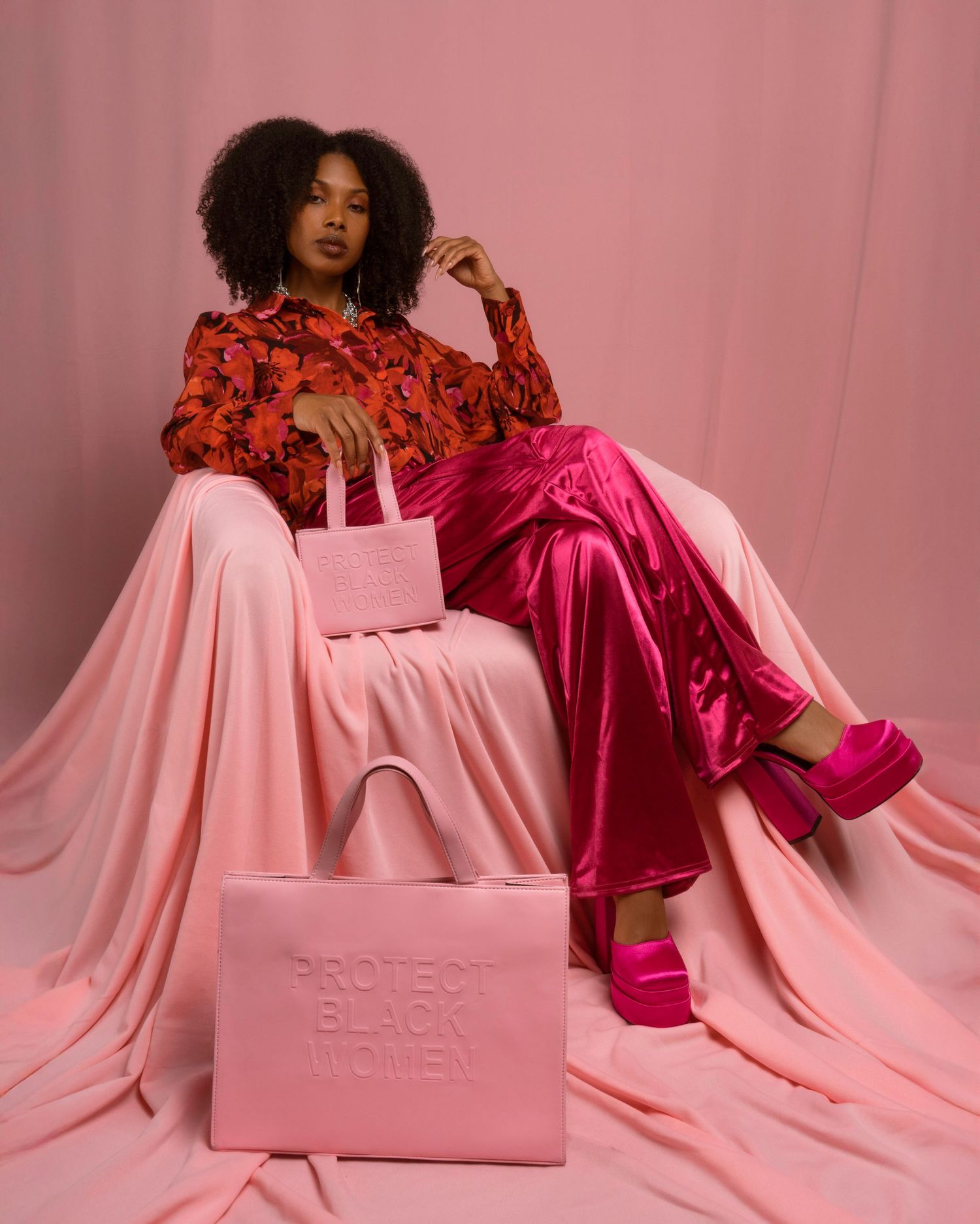 Fashion editorial featuring pink tote bags styled with red floral top and pink satin pants.