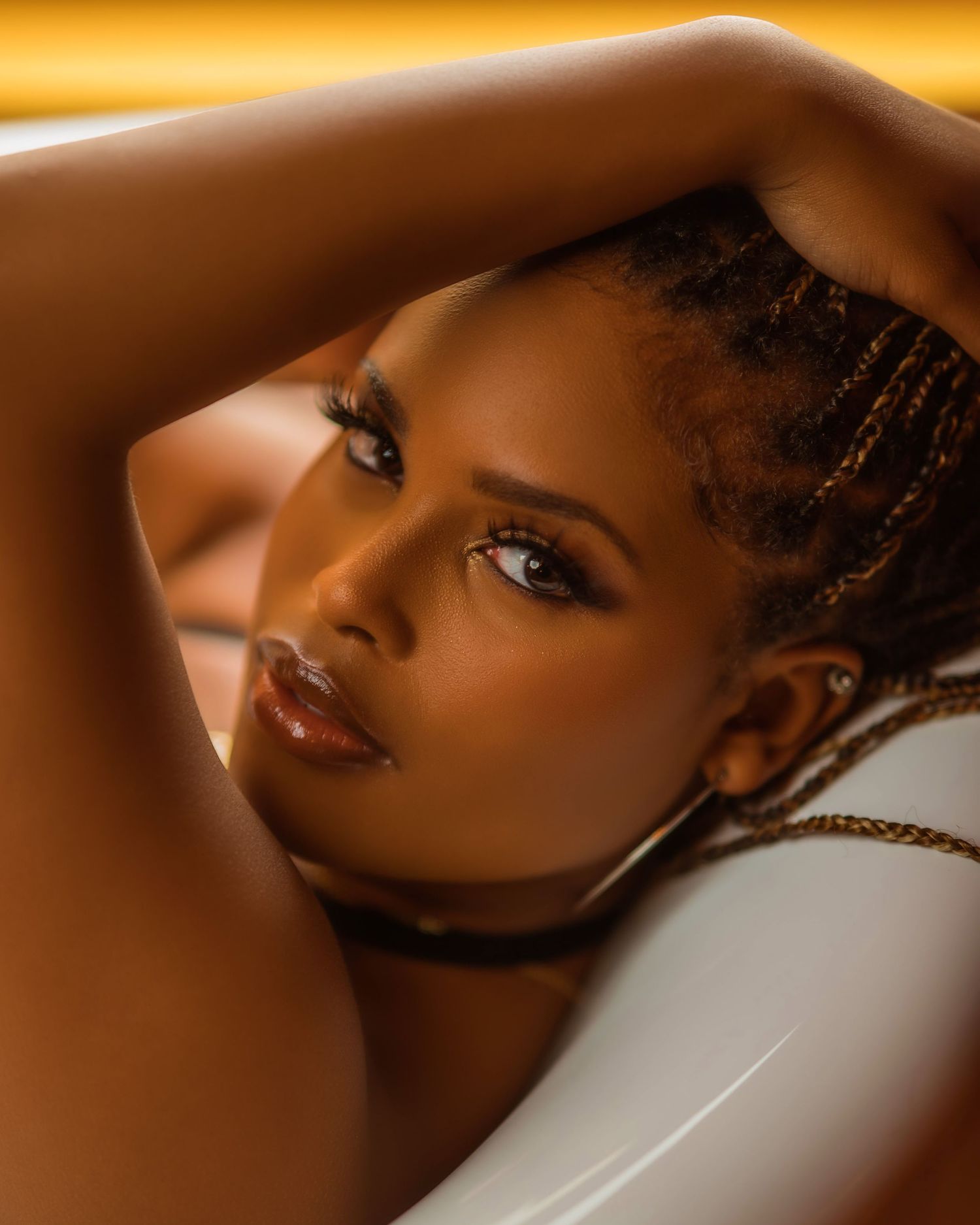 Warm-toned beauty portrait series with dramatic lighting against orange background.