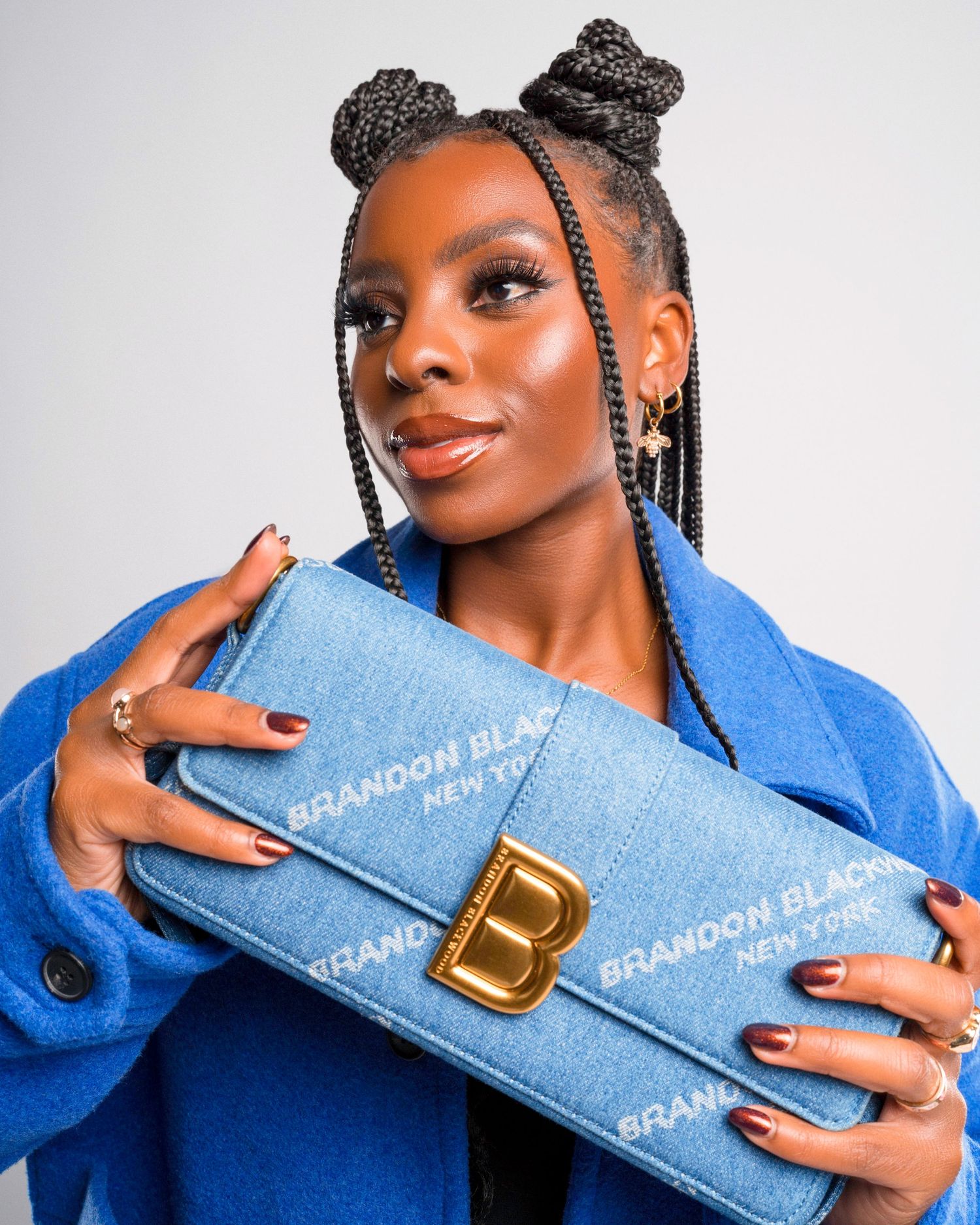 Light blue designer bag with gold hardware showcased with matching blue coat in studio setting.