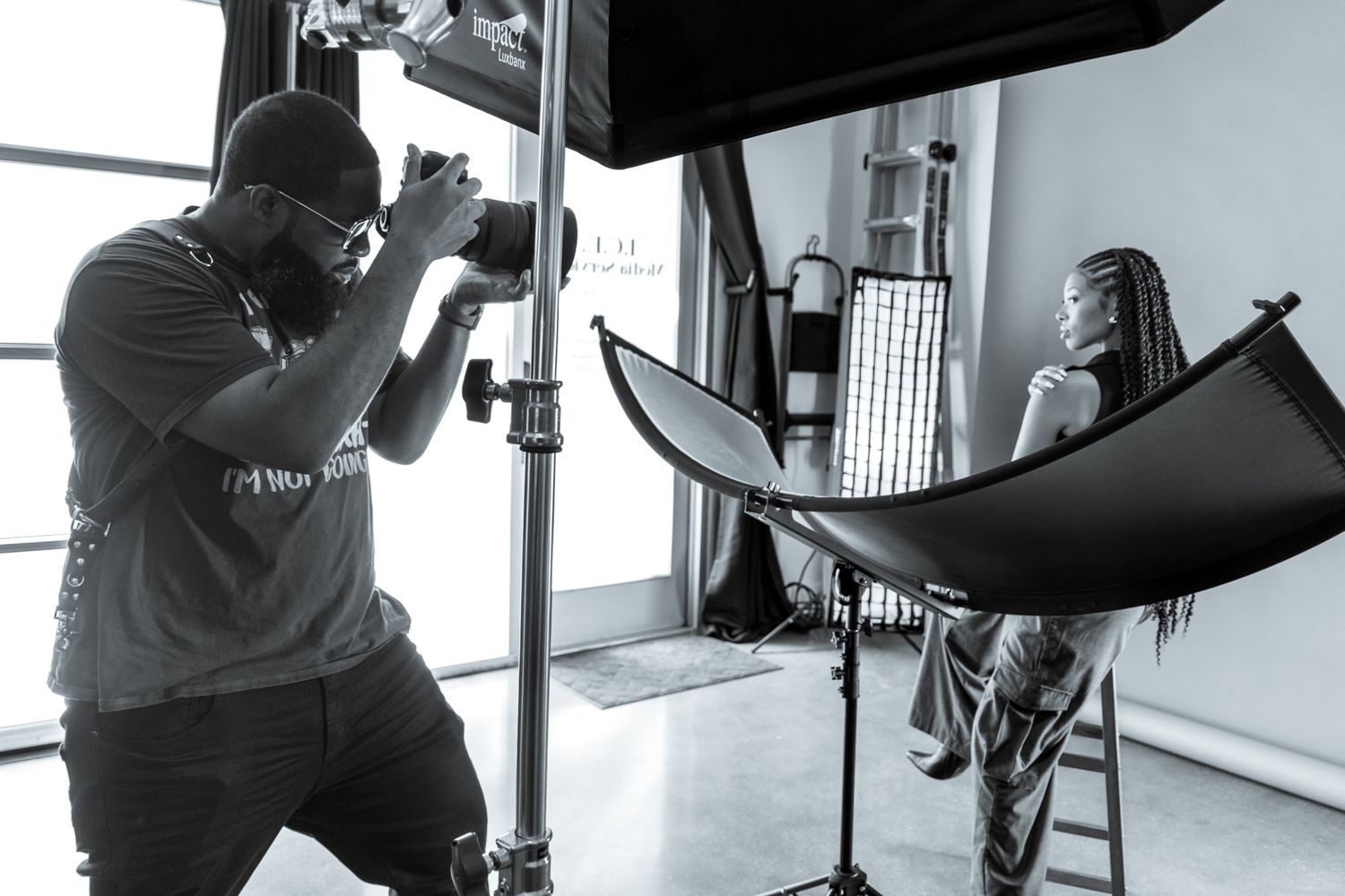Professional photographer working in studio with lighting equipment and camera setup during commercial photoshoot.