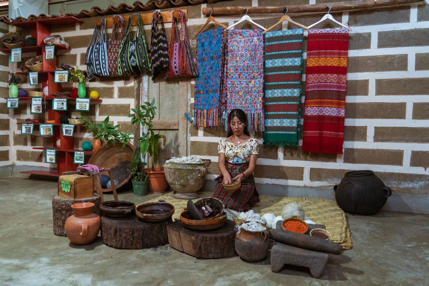 Colorful traditional Guatemalan textiles and handicrafts displayed along a white wall.