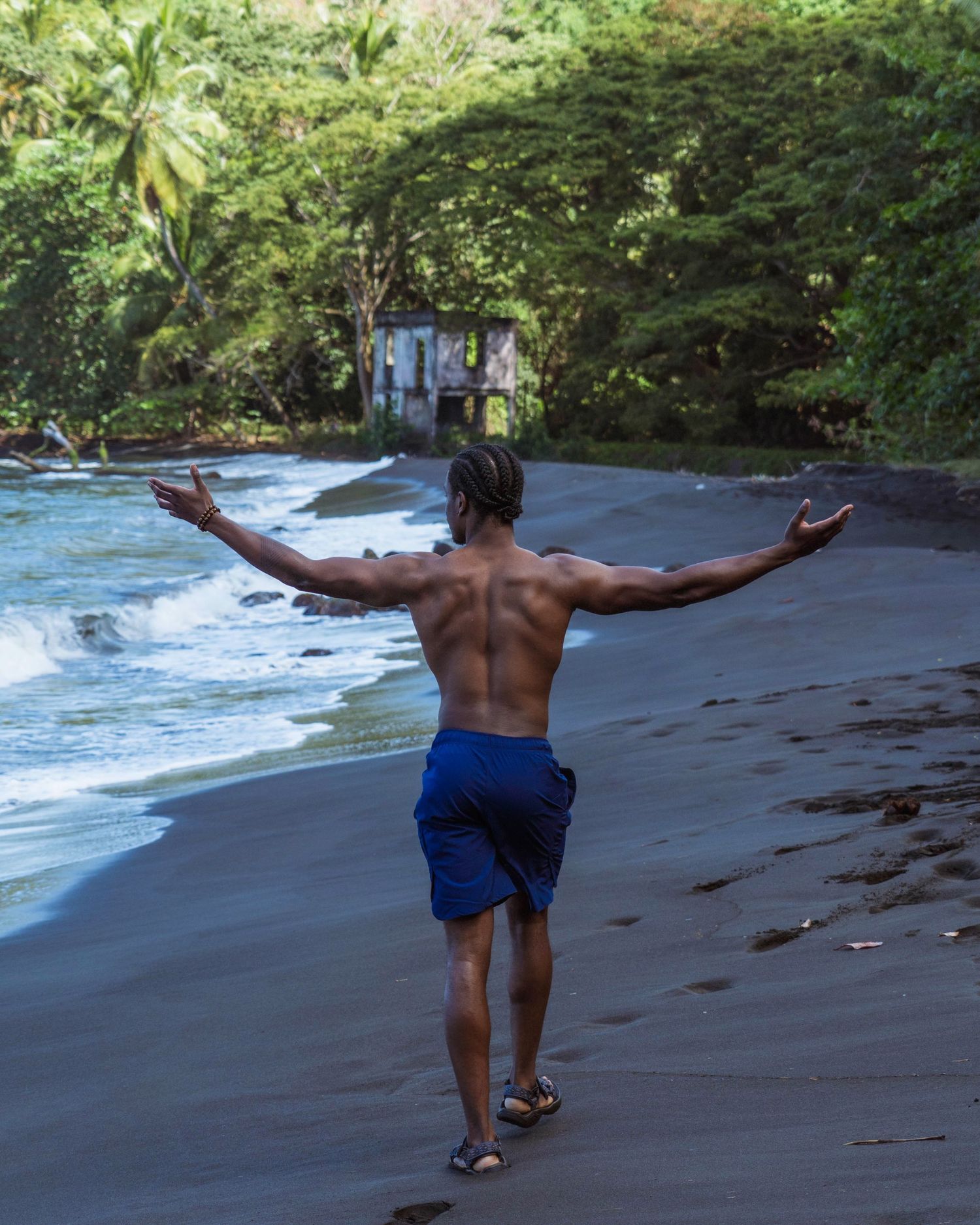 Isaiah Everett standing at the shore on a tropical beach in Grenada, arms open, capturing cinematic travel storytelling.