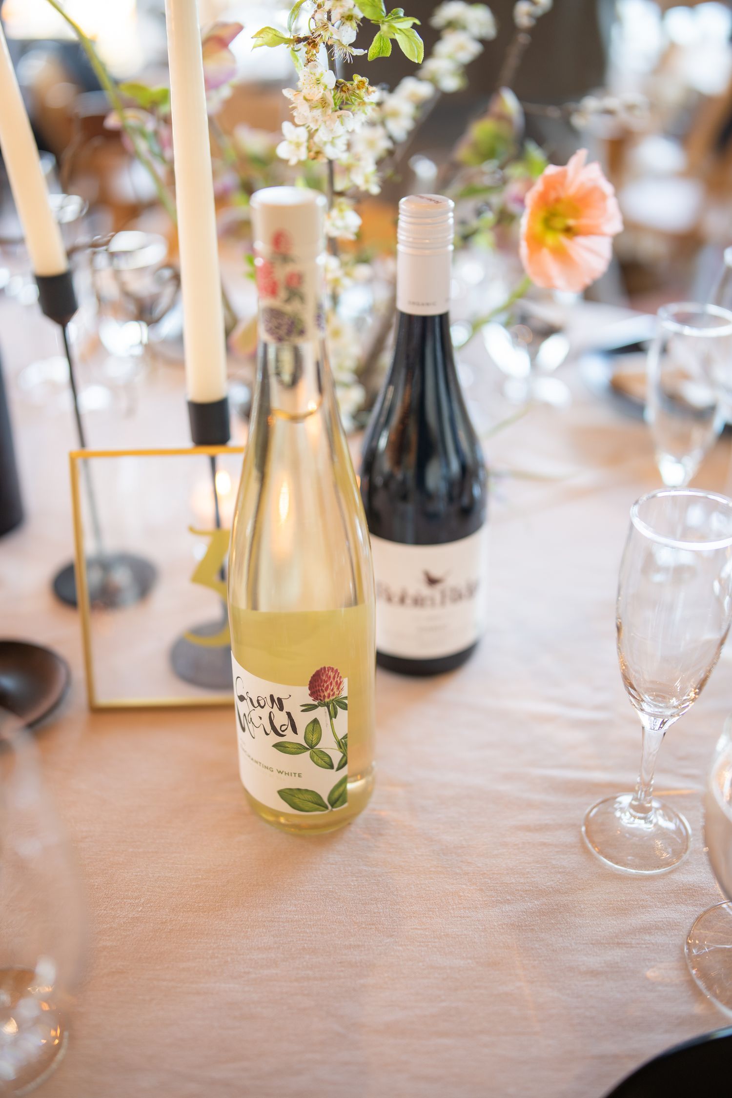 Elegant table setting with wine bottles, floral arrangements and glassware.