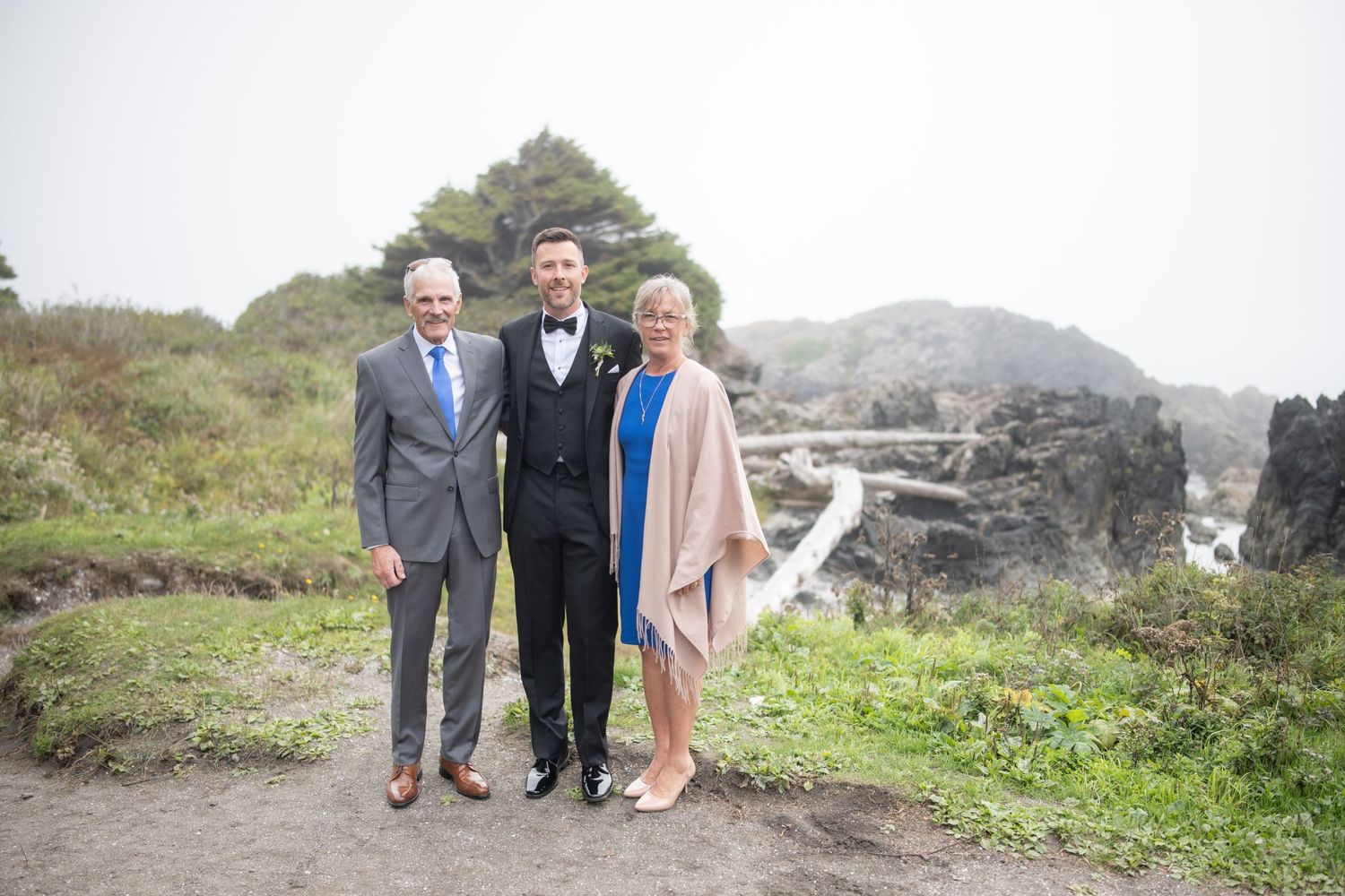 Wedding group portrait taken on rocky coastal landscape.