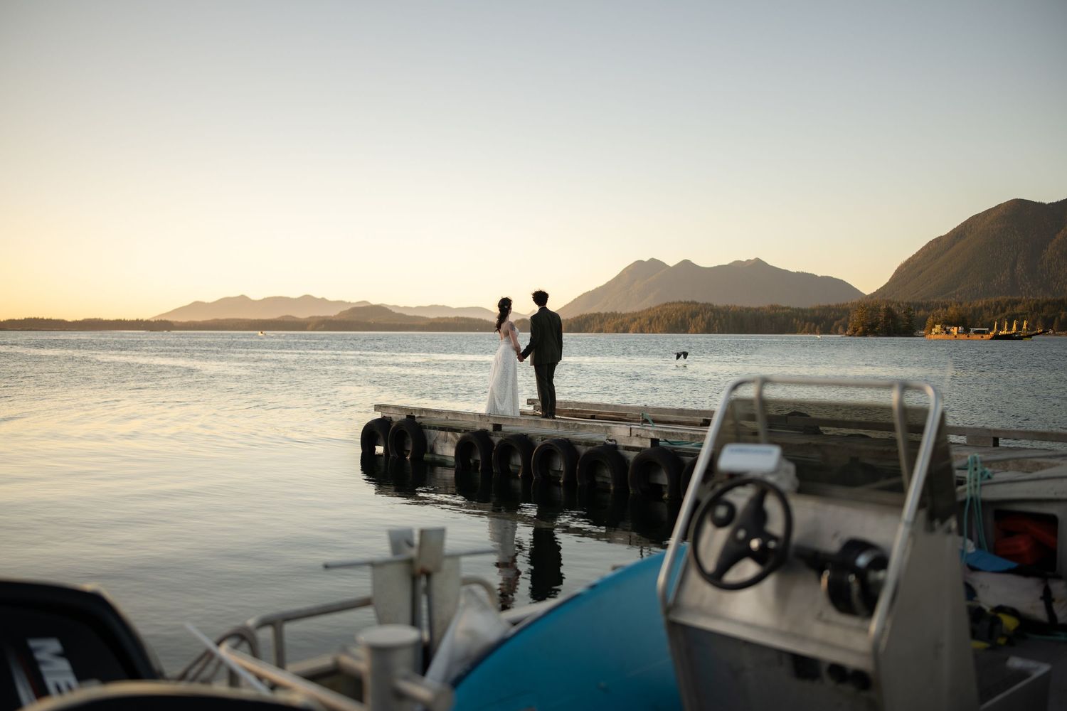 Scenic waterfront pier stretching into calm waters with mountains on the horizon at dusk.