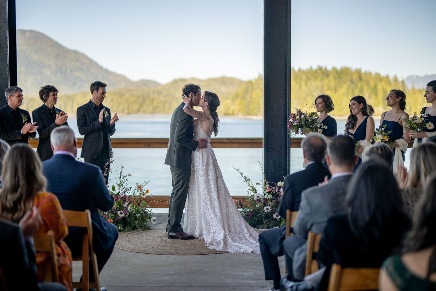 Wedding ceremony in progress at mountain venue with guests watching from wooden chairs.