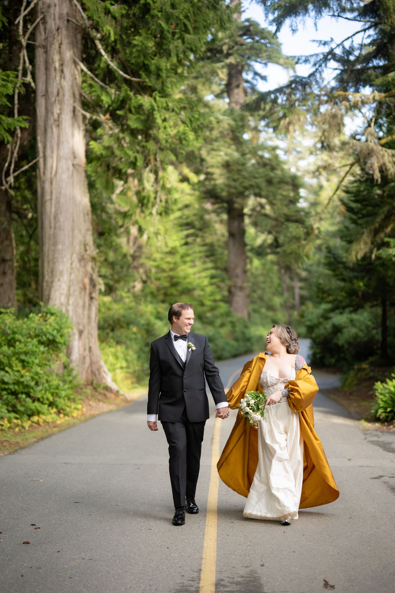 A couple walks along a tree-lined path, with a golden dress flowing in the breeze.
