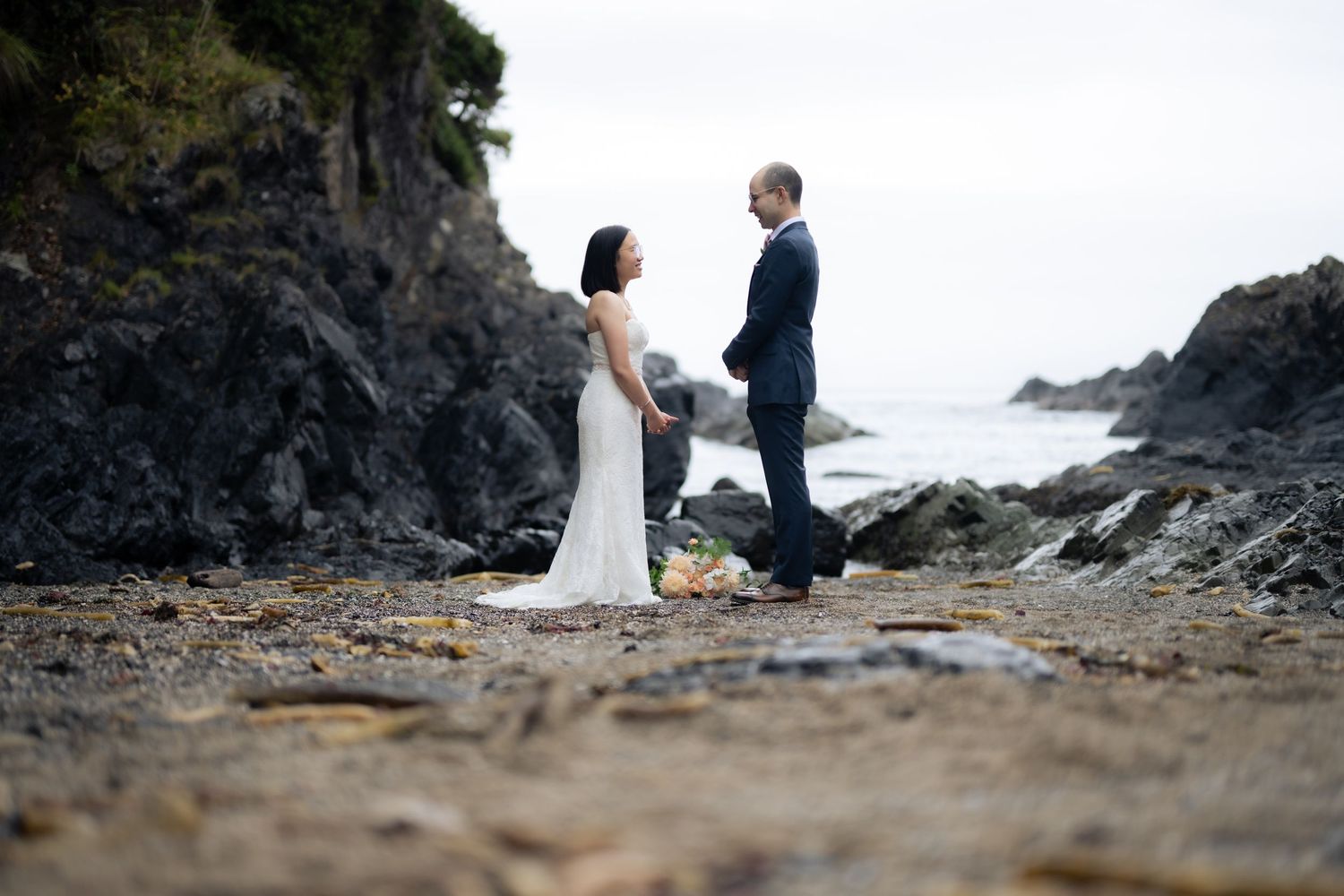 Intimate wedding ceremony on a rocky Pacific Northwest beach with dramatic coastal scenery.