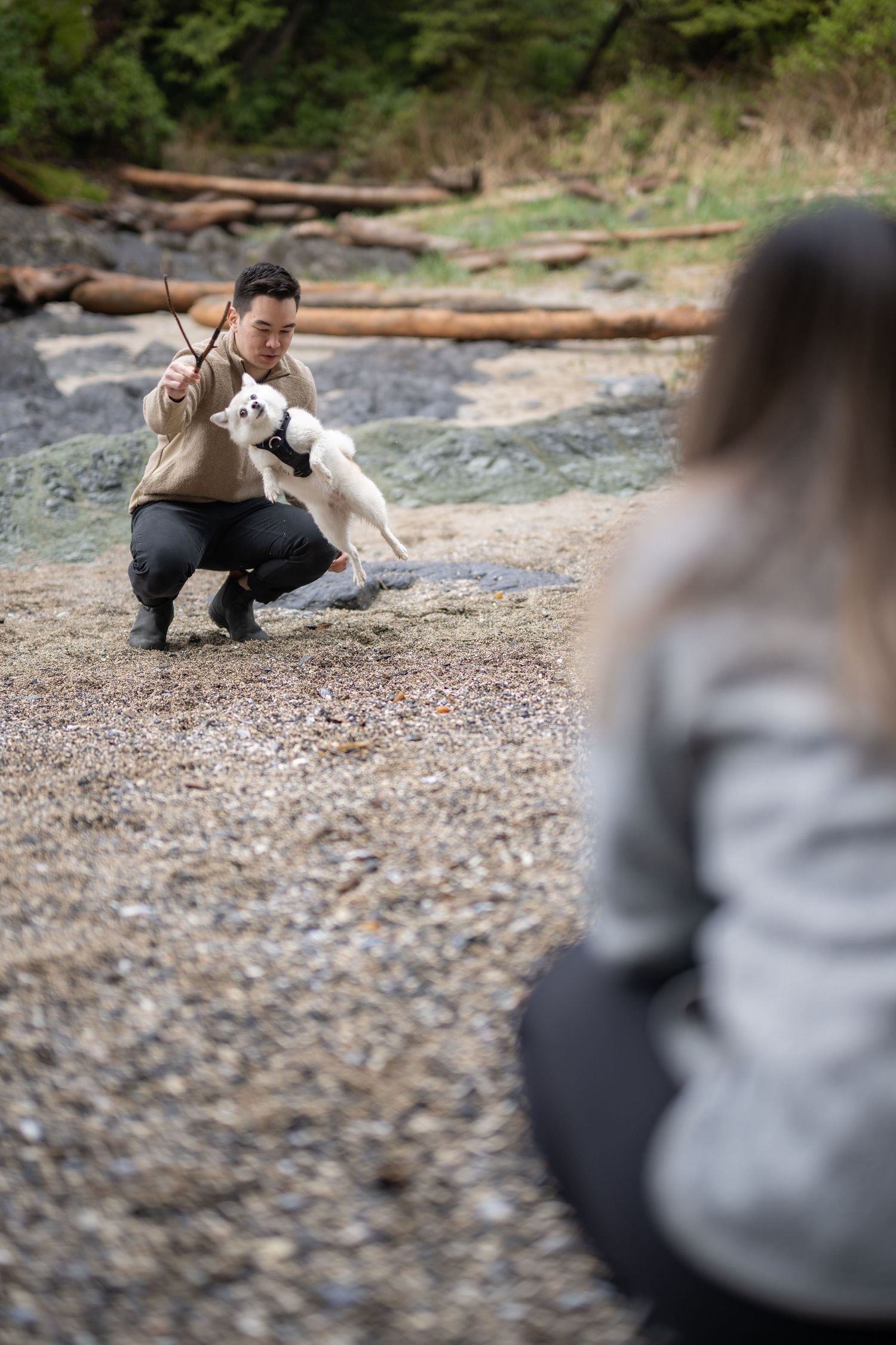 Person crouching on a rocky beach during a romantic photoshoot.
