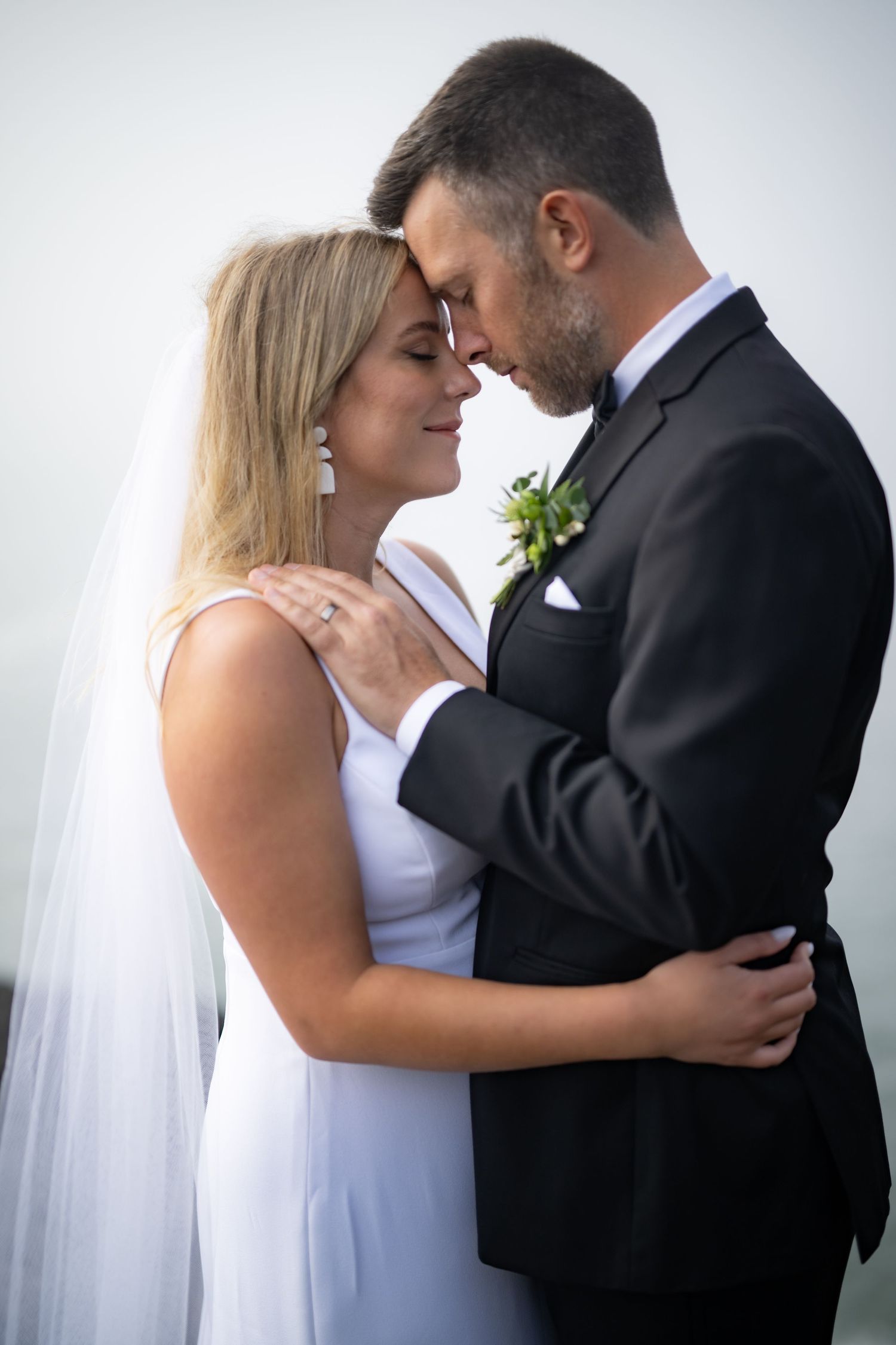 Romantic wedding couple shares intimate moments against a white backdrop in a series of tender poses.