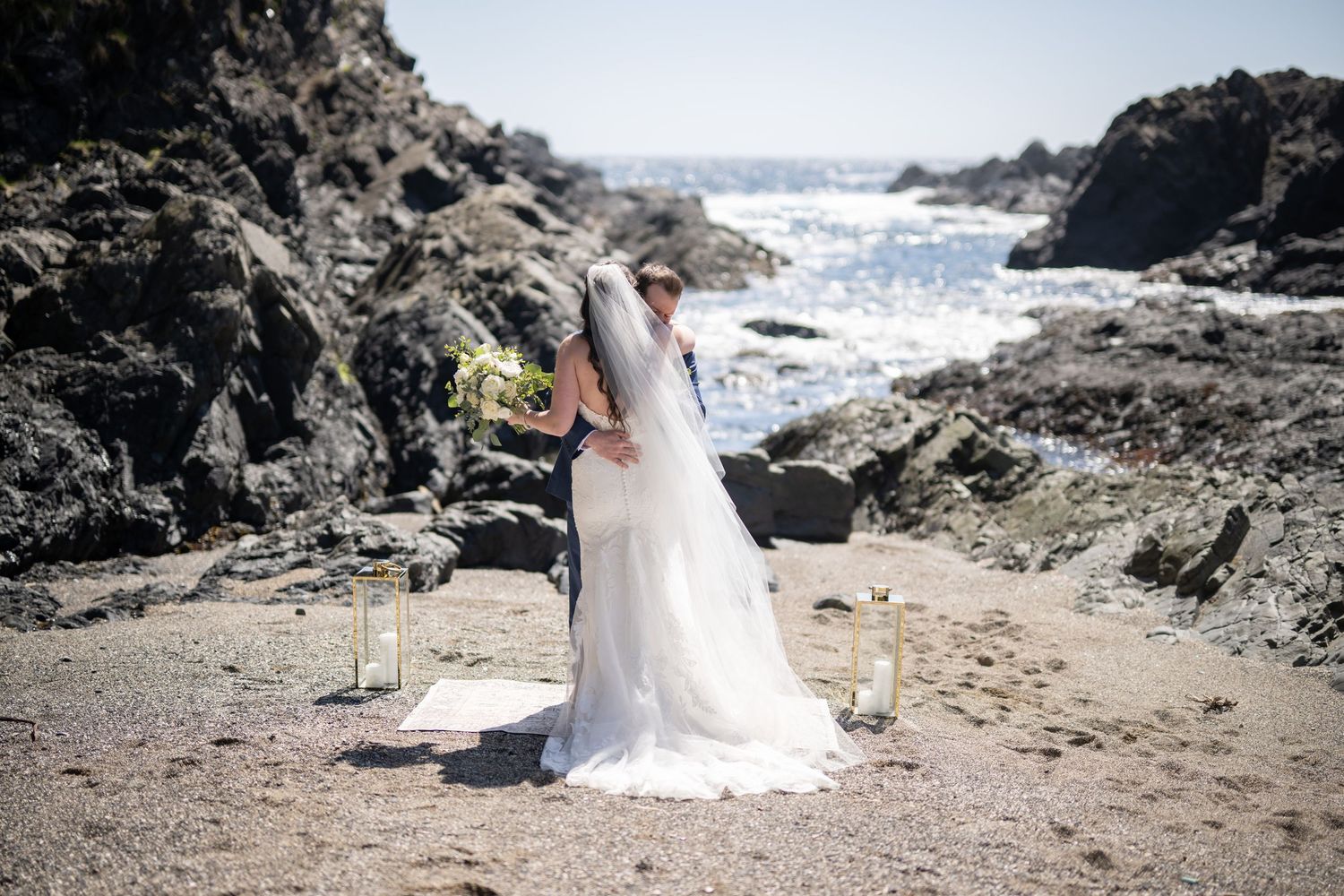 Wedding ceremony setup on a scenic rocky beach with ocean views.