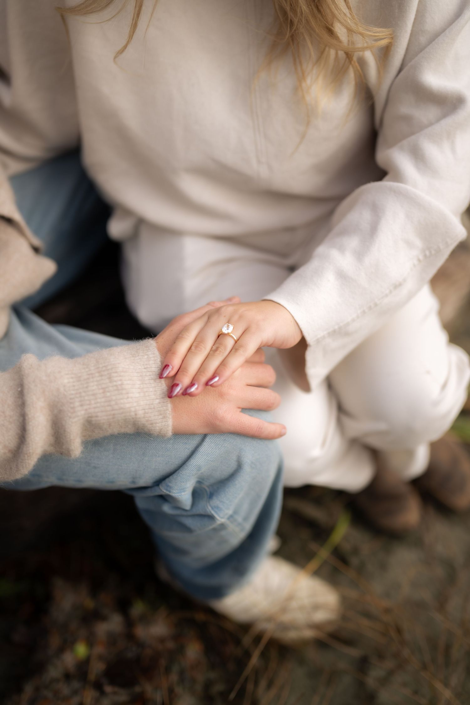 Close-up detail of white sweater and jeans while sitting outdoors.
